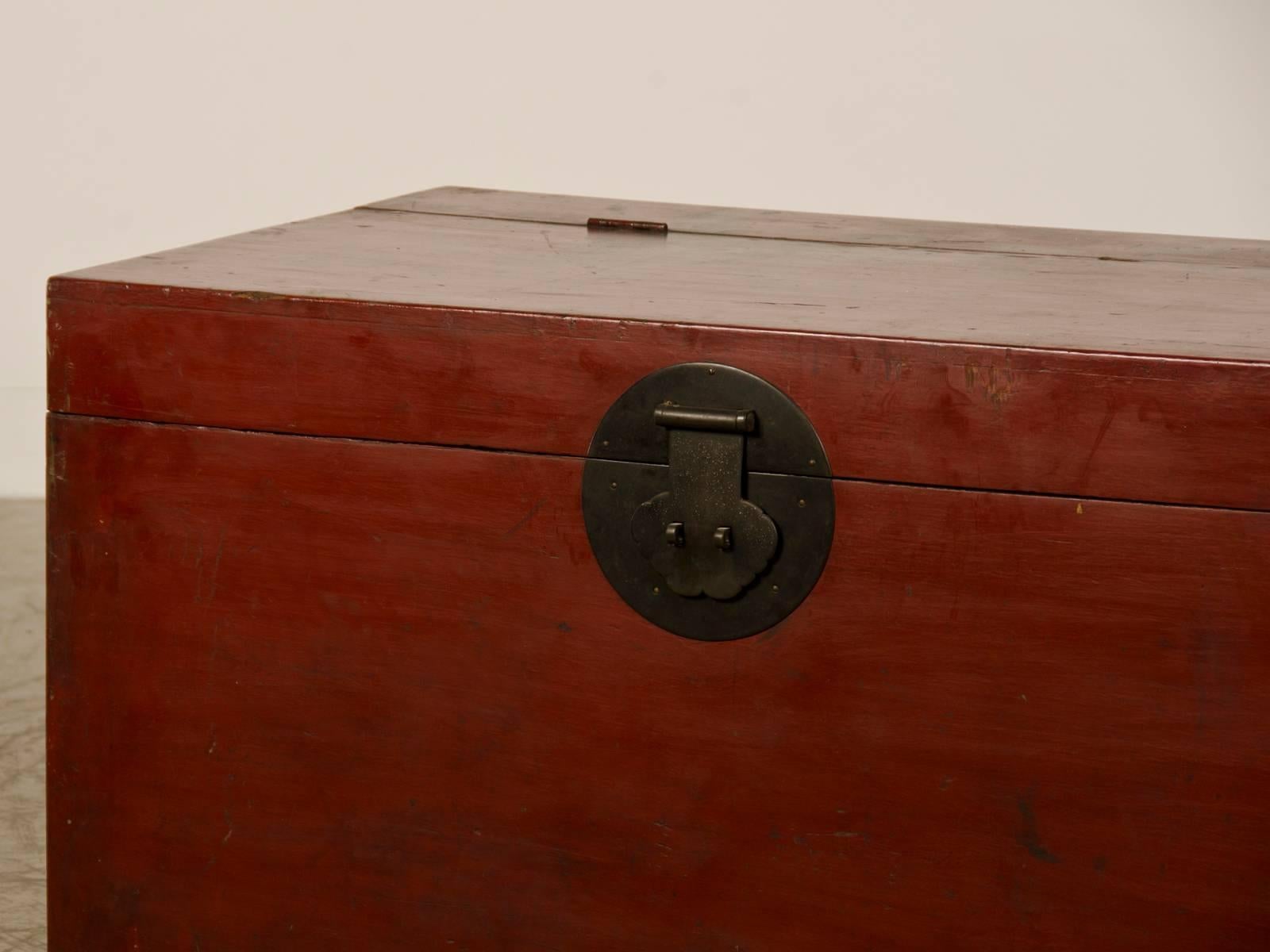 A large antique Chinese red lacquer trunk from the Kuang Hsu period in China, circa 1875 the original metal hardware. The trunk is slightly raised with a top that lifts to reveal the interior storage space. Because the trunk is finished on all four