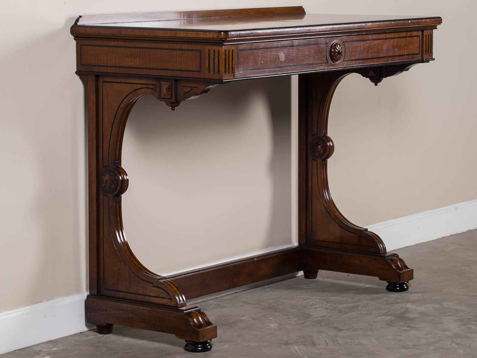 This elegant antique English mahogany console table, circa 1865 is embellished with ebonized wood stringing. The elegant sweep of the legs showcases the dramatic curved profile while enhancing the rounded corners of the top and front of the legs.