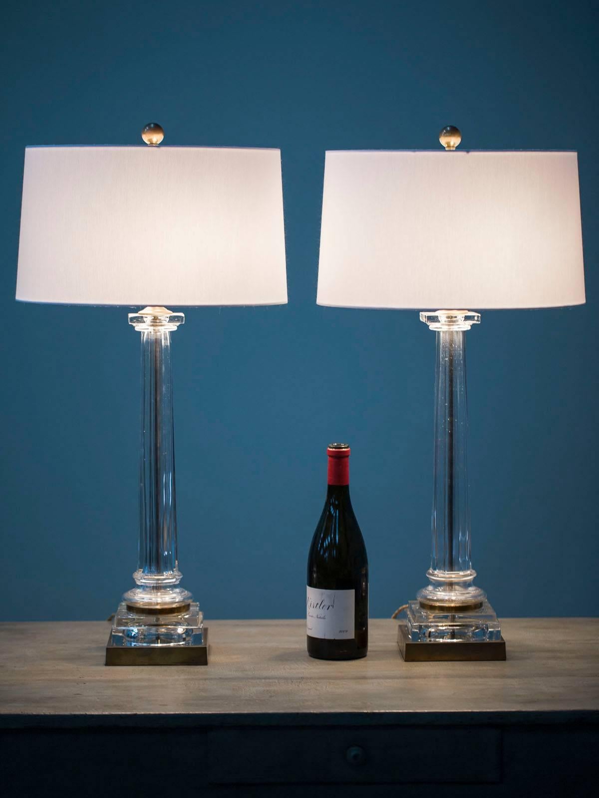 A smashing pair of vintage French solid glass and brass column lamps, circa 1940 now wired for American electricity. Each of the lamps feature a poured glass cylinder with a tapered shape as well as a textured surface. The glass surrounds a brass