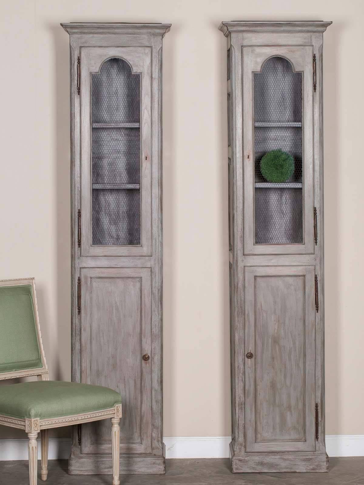 This pair of antique French painted oak cabinets, circa 1875, feature an upper and lower cabinet door with the upper door fitted with wire mesh. Please notice the architectural presence of these bibliotheque display cabinets as they Stand upon a