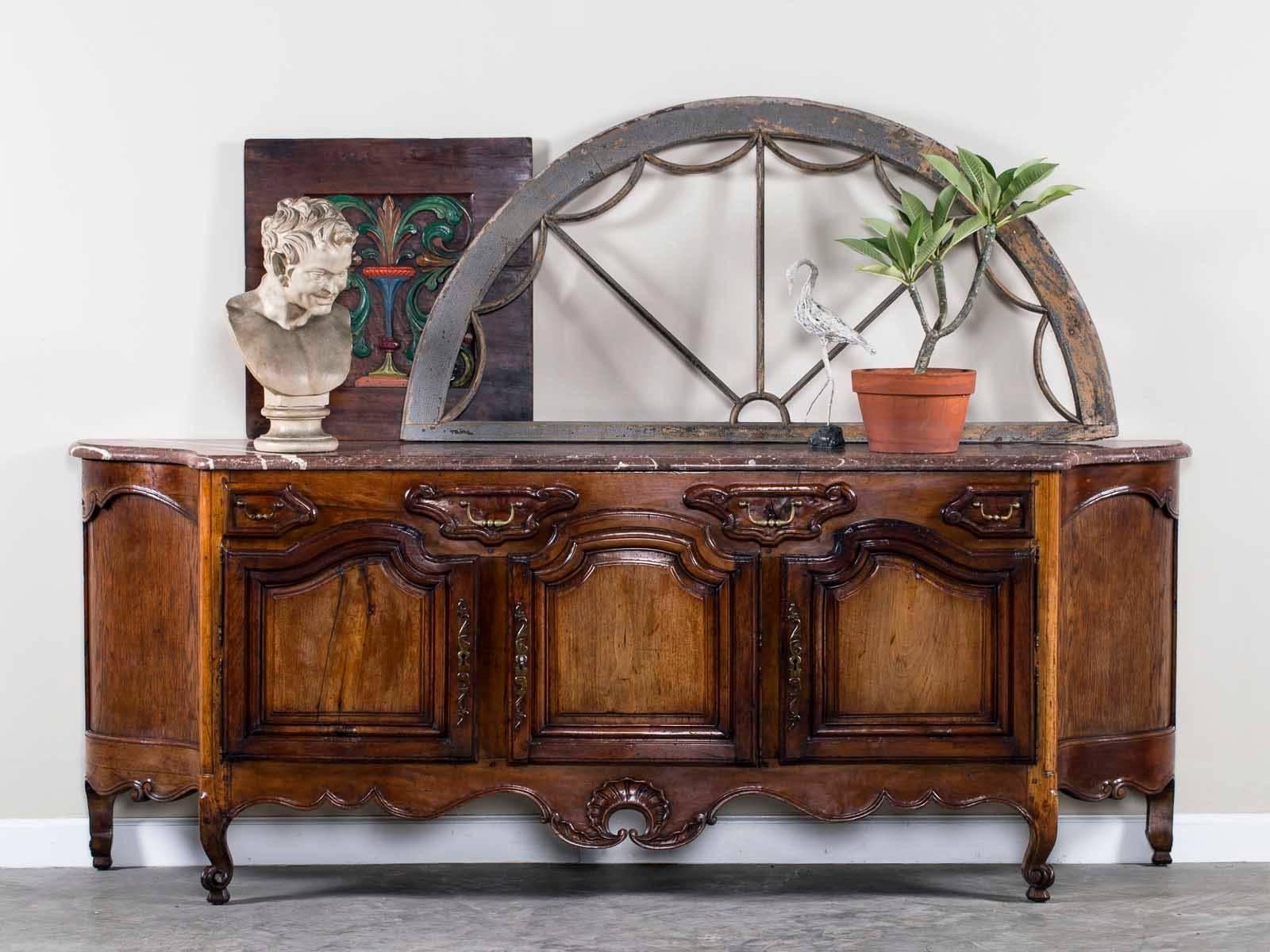 The sheer design exuberance seen on this antique French Louis XV walnut buffet credenza with its original marble top from France, circa 1780 is delightful. Of course this buffet was meant to function for both display, serving and storage but the