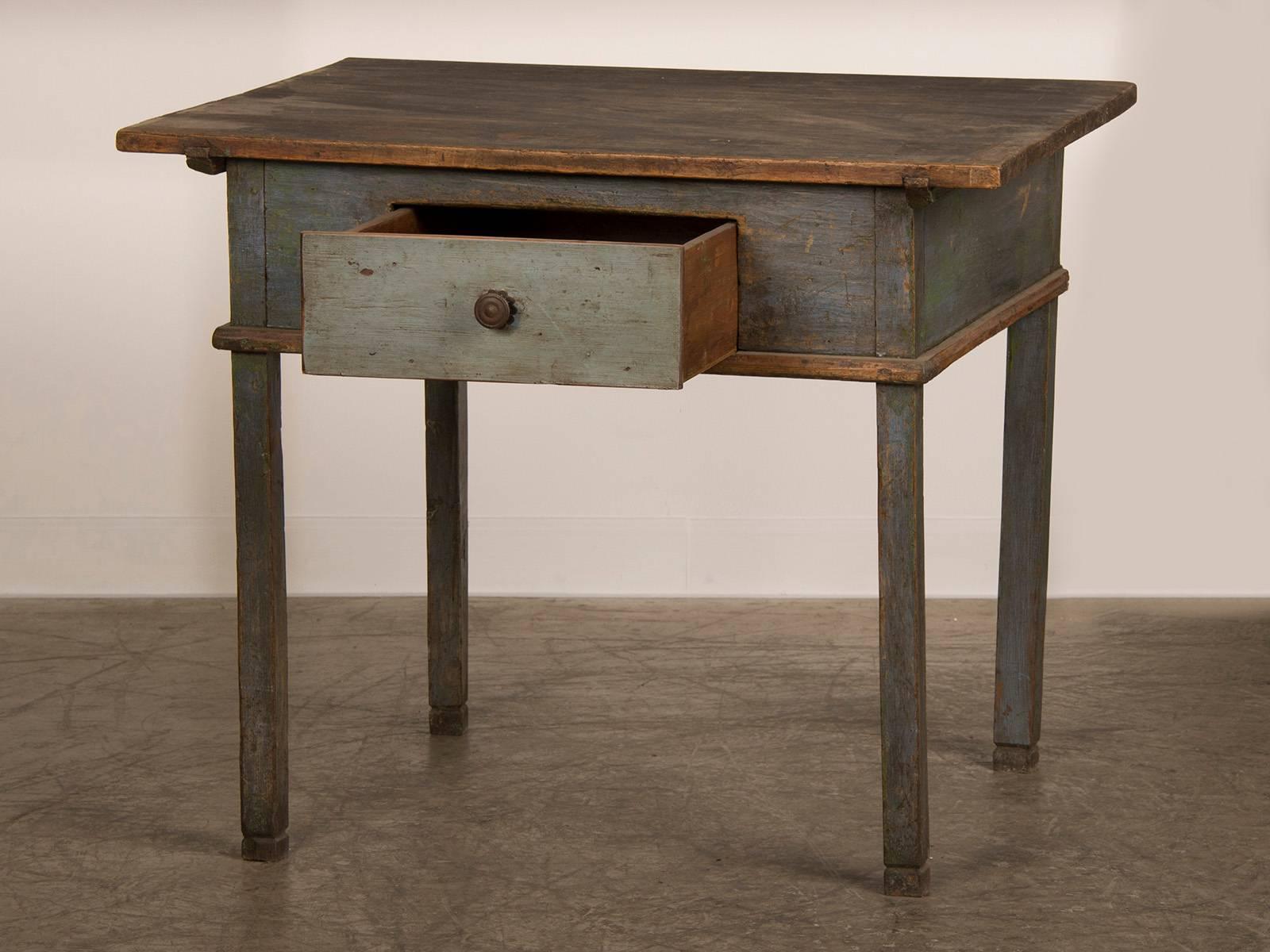An antique German workbench or writing table with the original painted finish having a single drawer, circa 1790. This table possesses a unique aspect because of the four square legs that support a substantial top. But small touches provided by the