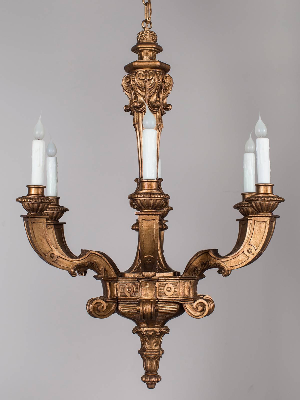 The six arms of this antique French carved giltwood chandelier, circa 1900, have a balanced and symmetrical placement around the central stem seen during the Louis XVI period. The burnished gleam of the gilded finish enhances the lovely carved