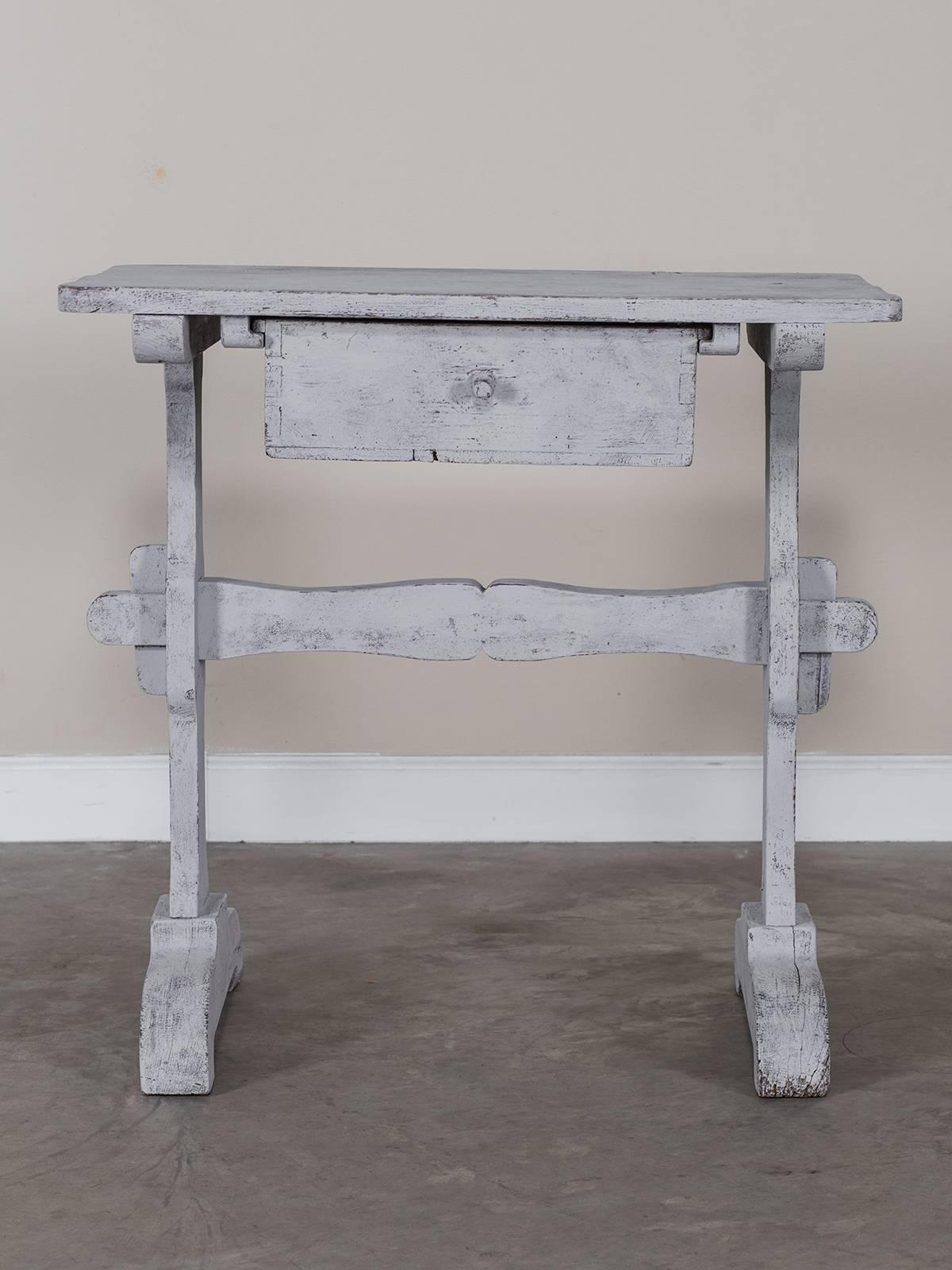 A rustic antique French painted pine side table circa 1870 having shaped side supports and a drawer beneath the rectangular support.