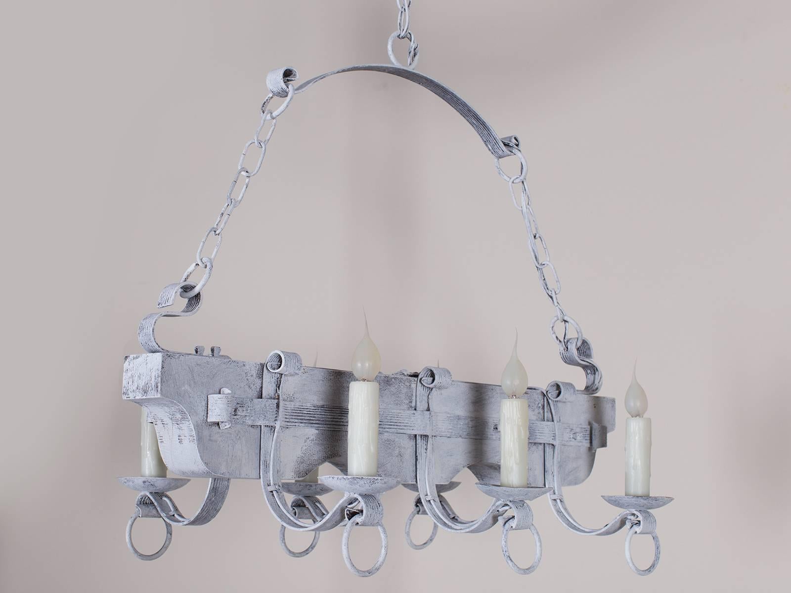 A vintage French painted wood and iron chandelier circa 1940 with an interesting arrangement of iron strap work supporting the candle arms. This fixture is reminiscent of the antique ox yoke chandeliers and has been rewired for American electricity.