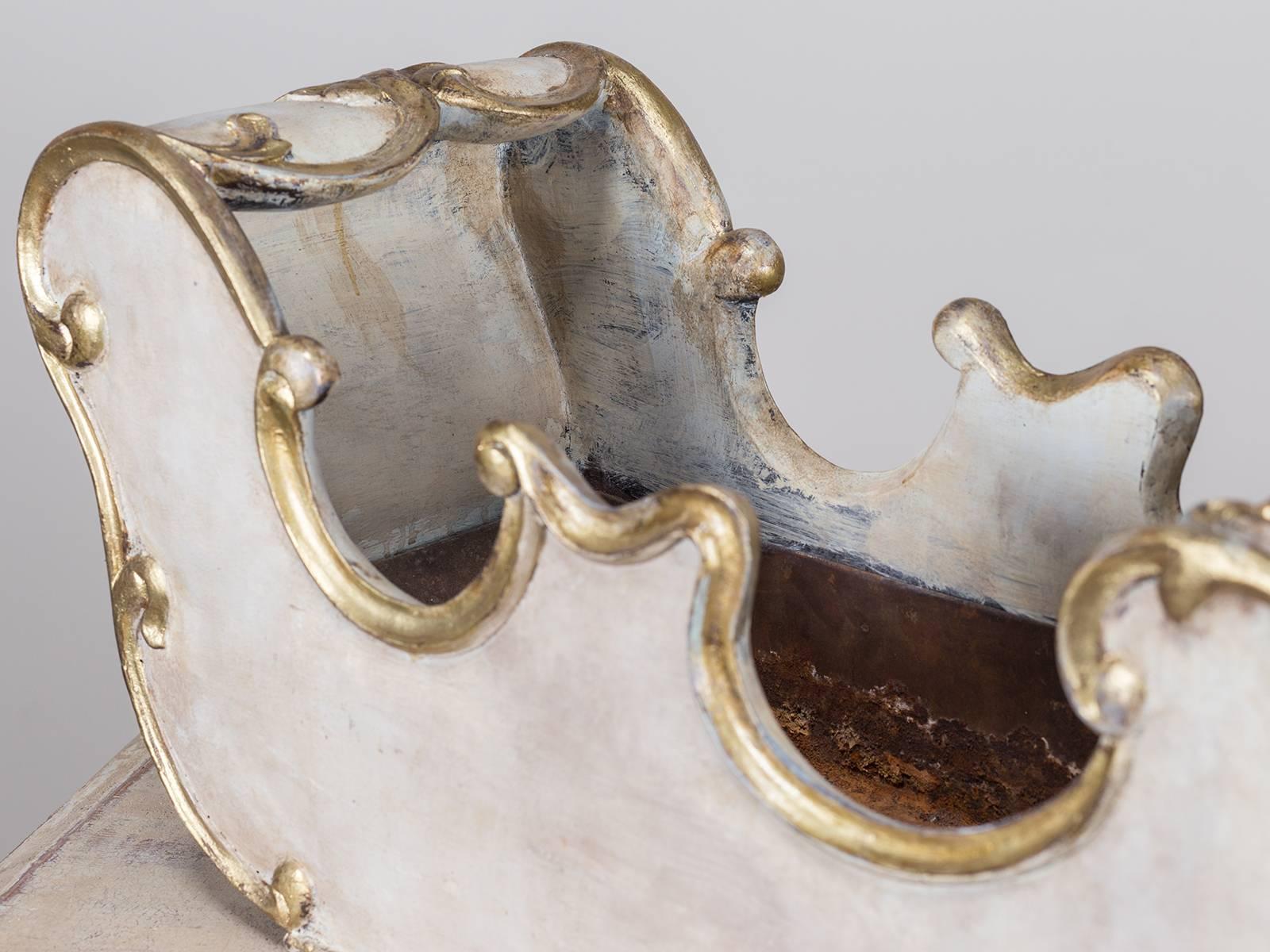 This charming vintage French plant holder circa 1940 in the shape of a sleigh has a painted and gilded finish that conceals a liner for potted plants. In the Rococo style with scrolls and flourishes this unusual carved wood container is perfect for