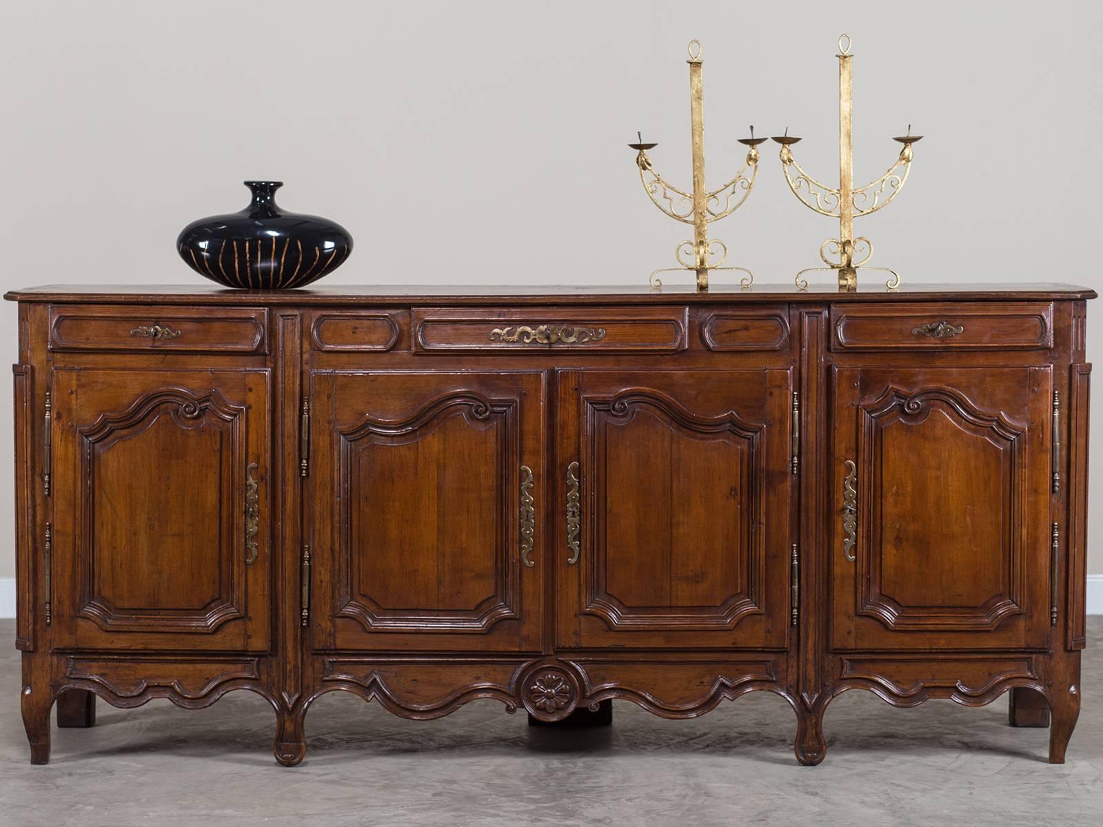 The elegant balance of the decorative details on this 18th century French buffet or credenza showcases the superb skill of cabinet making in France. Please note the symmetry of the moulding on each of the four cabinet doors with each upper section