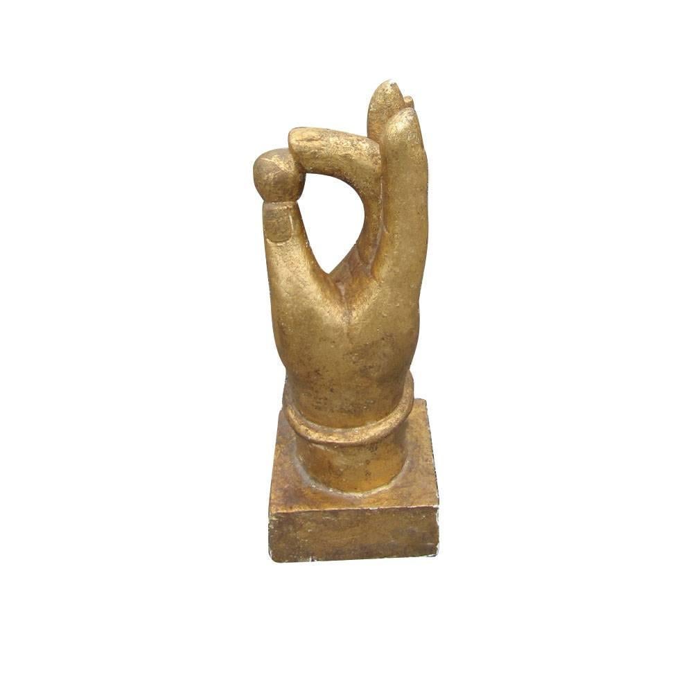 Metallic gold hand statue on a square wooden base designed to form
the A-OK hand-gesture. Thumb and forefinger are holding a small ball.