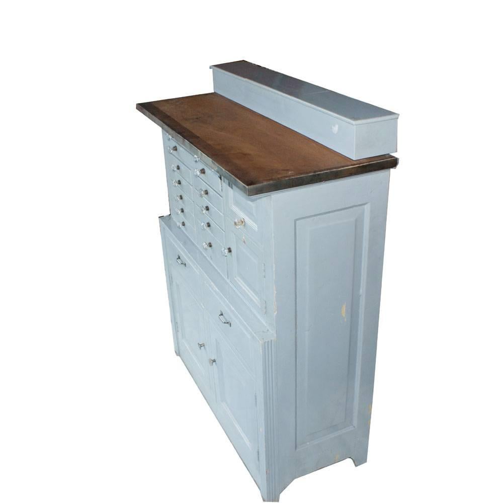 13 wood instrument drawers. 
Top shelve has three boxes.

Multiple pull-out drawers, each with faceted glass pulls.

Pull up small door revealing extra storage.

Right door with internal partitioned drawer.

Two of the drawer have metal