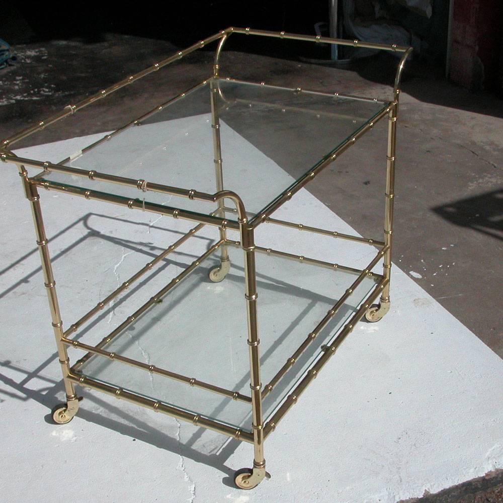 Hollywood Regency styled brass finished faux rattan bar cart with glass tops comes with style and mobility fit for any room. With comfortable sleek dimensions fit for hosting refreshments, condiments or displaying decor.