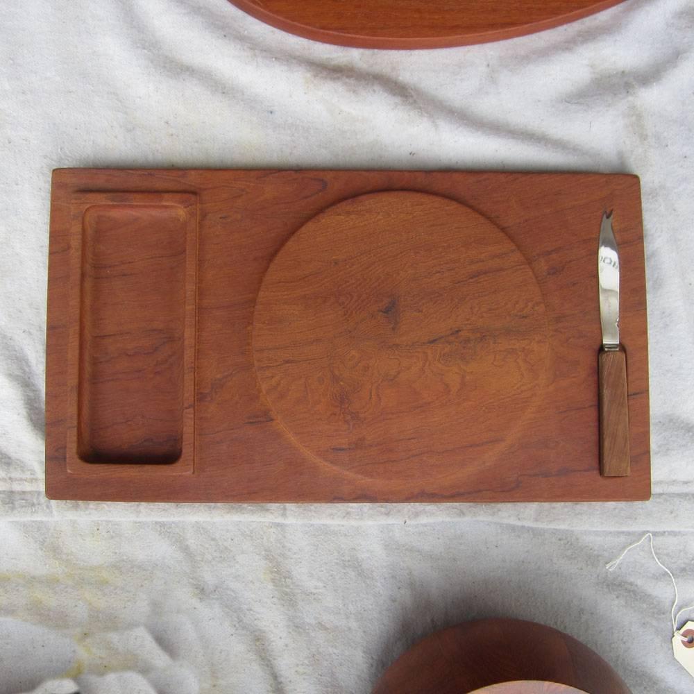 A vintage teak cheese tray from Galatix that includes a knife and a bowl. The burl on this wood looks amazing and many fine details really add to the appeal of this piece, from the raised edges in the dipping groove, to the teak knob on the acrylic