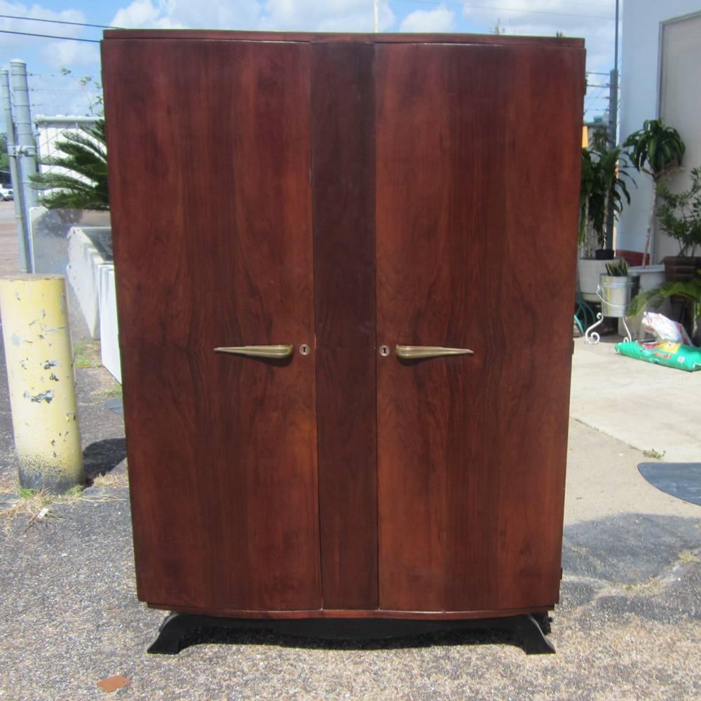 A vintage Mid-Century French mahogany double door armoire. This wardrobe has large area with a wooden bar for hanging clothes and a smaller compartment above it that can hold smaller folded clothing. A really lovely vintage piece. 

Measures: