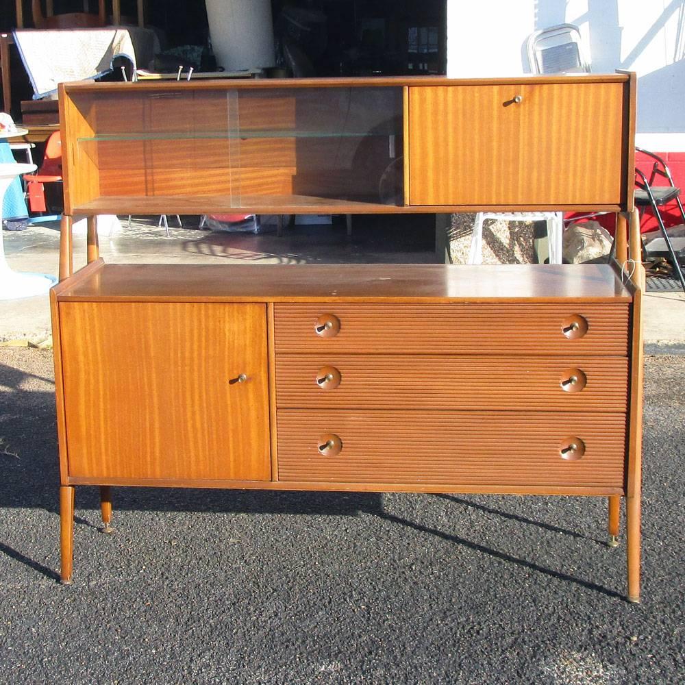 Vintage Mid-Century sideboard buffet.
This sideboard has ample storage below and overhead. Three drawers below wit two shelves. Glass shelves overhead with a pull down cabinet.

