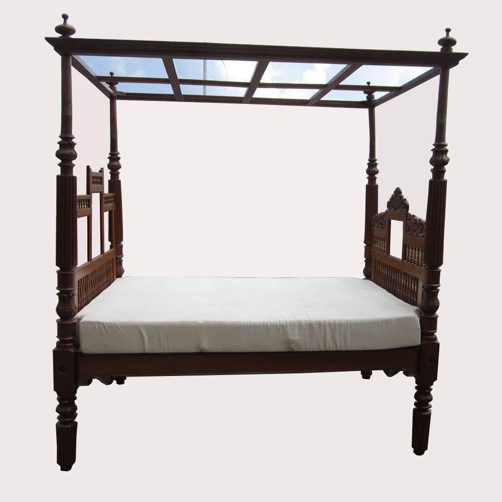 A vintage Indian bed featuring a canopy made of solid hand-carved teak This bed frame features a multitude of details in the wood from the turned columns to the carved flower motifs hidden throughout the bed.  Mattress is not included.