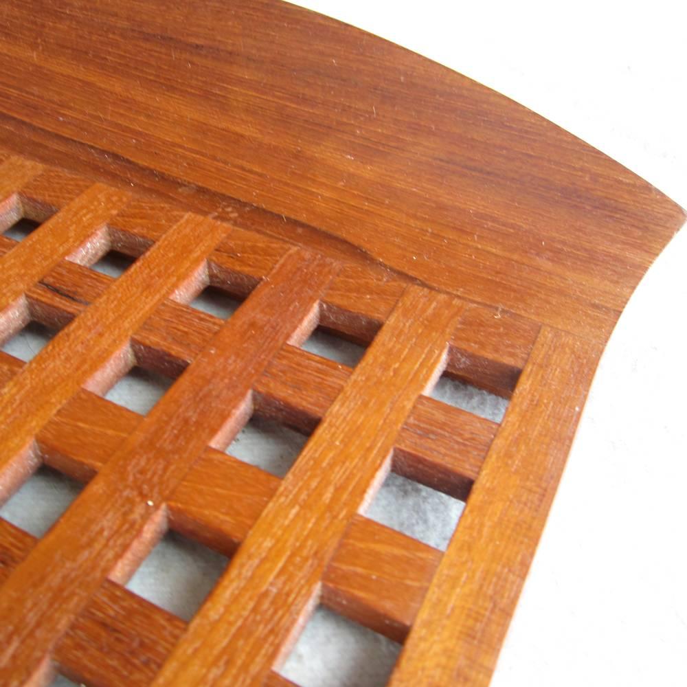 A set of vintage Dansk lattice trays and trivets made of solid teak. The two trays with handles were designed by Jens Quistgaard and bear the characteristics of all of his designs. The smaller trivets without handles are from a later production and