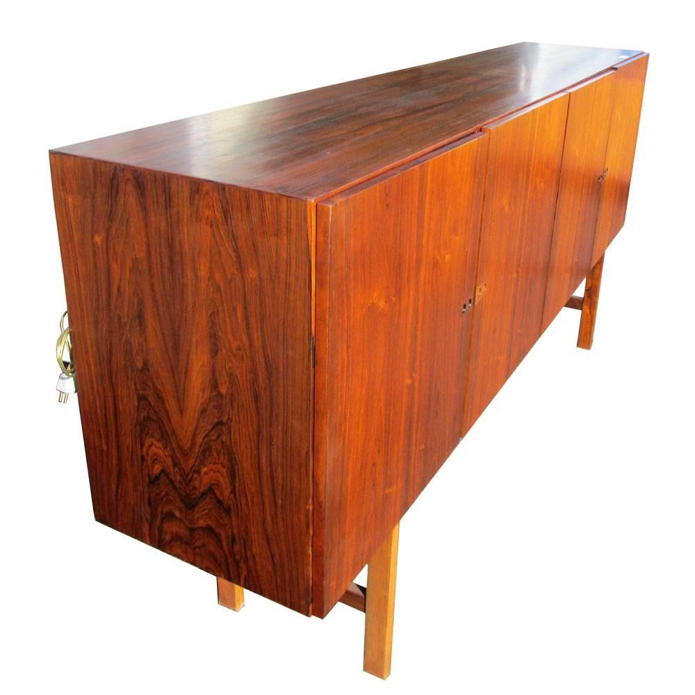 Vintage large credenza in rosewood produced early in the 1960s by Faarup Møbelfabrik and designed by Ib Kofod Larsen 
In-cabinet Light with inner mirror. Adjustable shelves, three lined felt drawers and two regular drawers 
Circa 1960s 
Made in