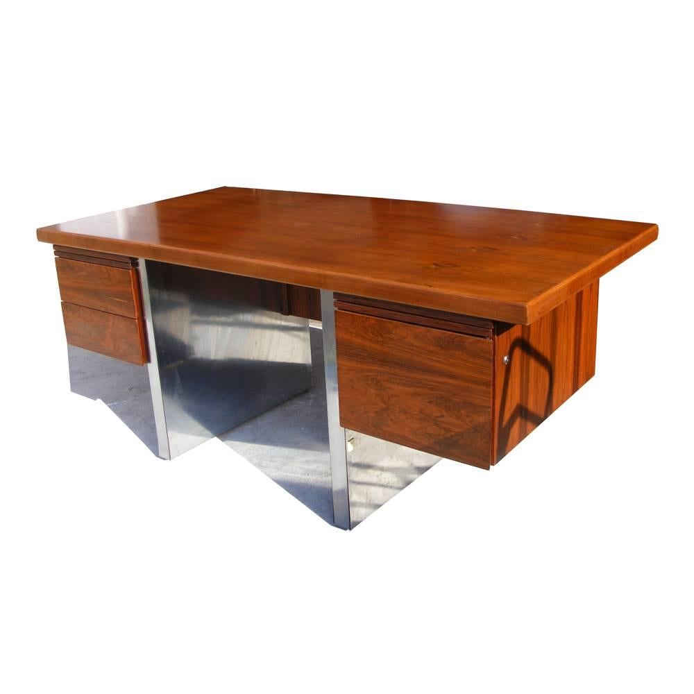 Una scrivania direzionale in stile Mid-Century Modern di Roger Sprunger. Palissandro con base a doppio piedistallo in acciaio inox. Tre cassetti di cui uno schedario e due normali con due tavolette estraibili.