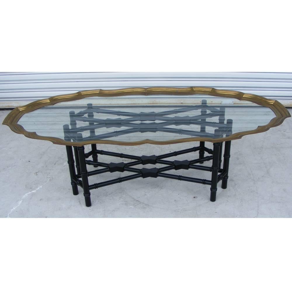 A mid century modern coffee table made by Baker with an ebonized faux bamboo base and brass and glass top.