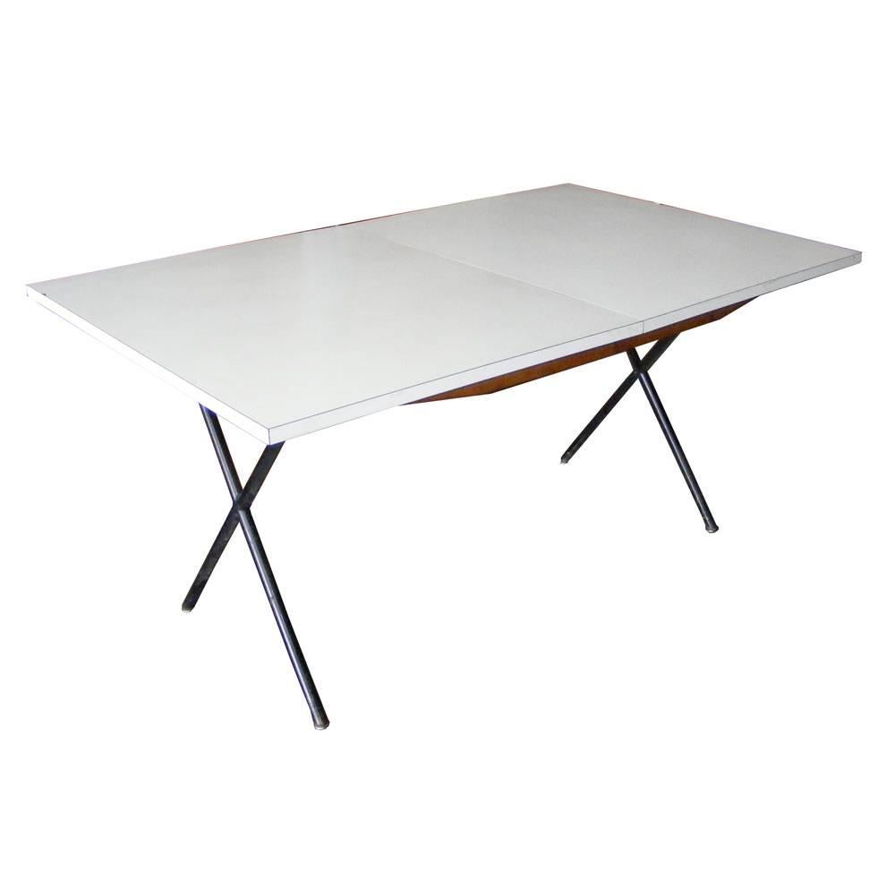A mid century modern dining table designed by George Nelson and made by Herman Miller.  Black meatl X-legs with a white laminate top.  The table expands from 60" to 76".