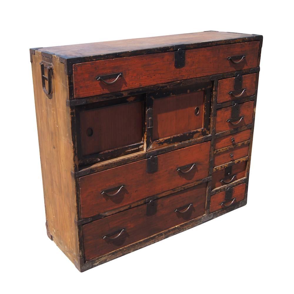 This fine age appropriate cabinet sits with technique and tradition from the Meiji Period that can be dated back to the late 1860's. With cast iron pulls on 8 drawers, this tansu also features a sliding door cabinet that allows for display purposes