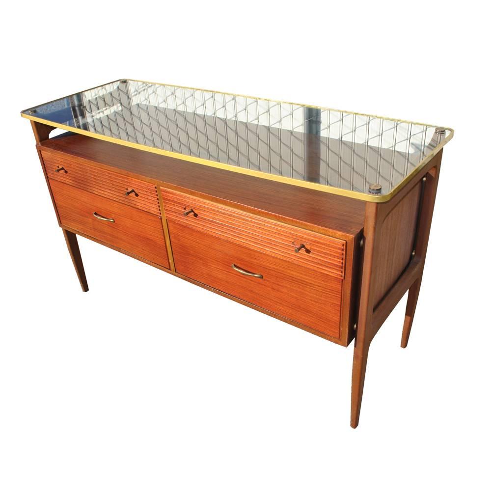 A lovely mid century modern walnut Wrighton cabinet with floating glass top that could be used as  a credenza, a vanity, or a bar.

Distinctive floating form suspended on slim tapered legs with
two small upper partitioned desk drawers, drawer with