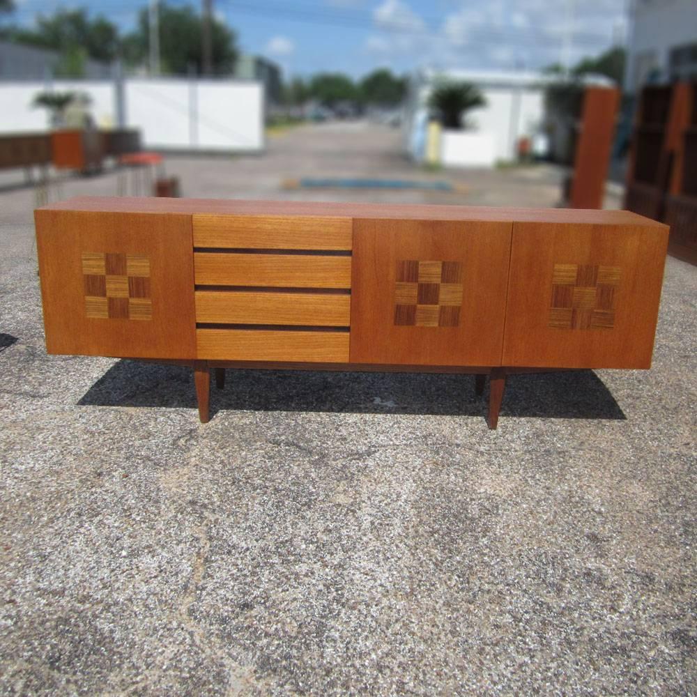 A vintage rosewood and teak credenza designed in the 1960s midcentury period. This simple yet elegant sideboard has four drawers (with utensil drawer) with three adjustable shelves. Parquet details. Measure: 84