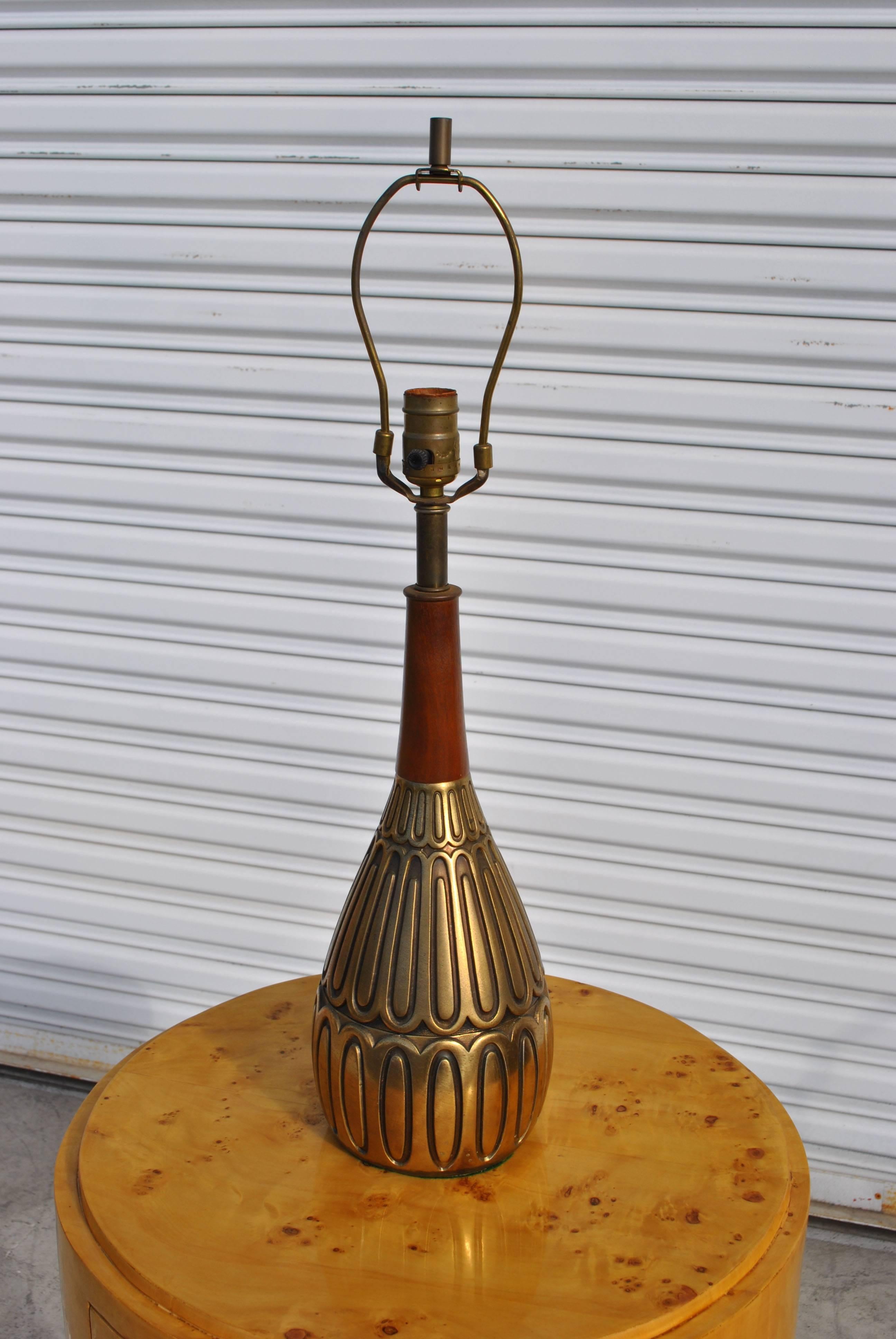 Unique vintage midcentury lamp in brass and walnut 


Lamp is wrapped in elliptical patterned brass with a teak base. 

Wired and working.
       