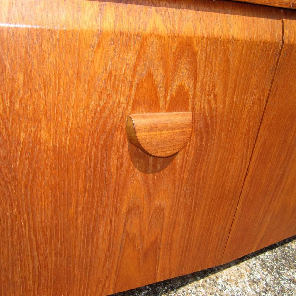 A vintage European oak credenza manufactured in the 1960s with unique drawer pulls and door handles. Three top drawers with one for flatware. Pull down bar cabinet. Size: 78”.