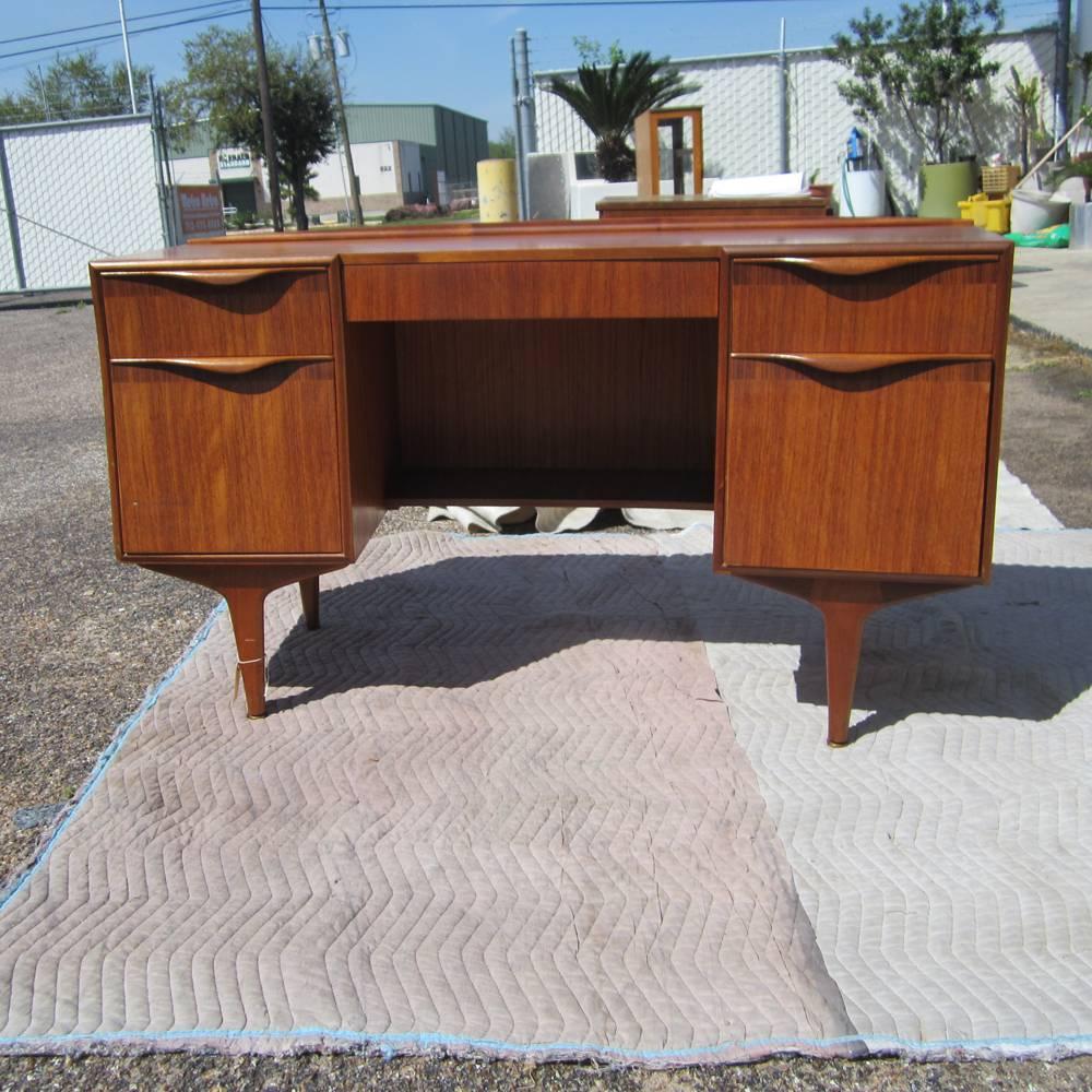 A midcentury mahogany four-drawer desk. Tapered legs and curved desktop. 
Five drawers including two file drawers.
 