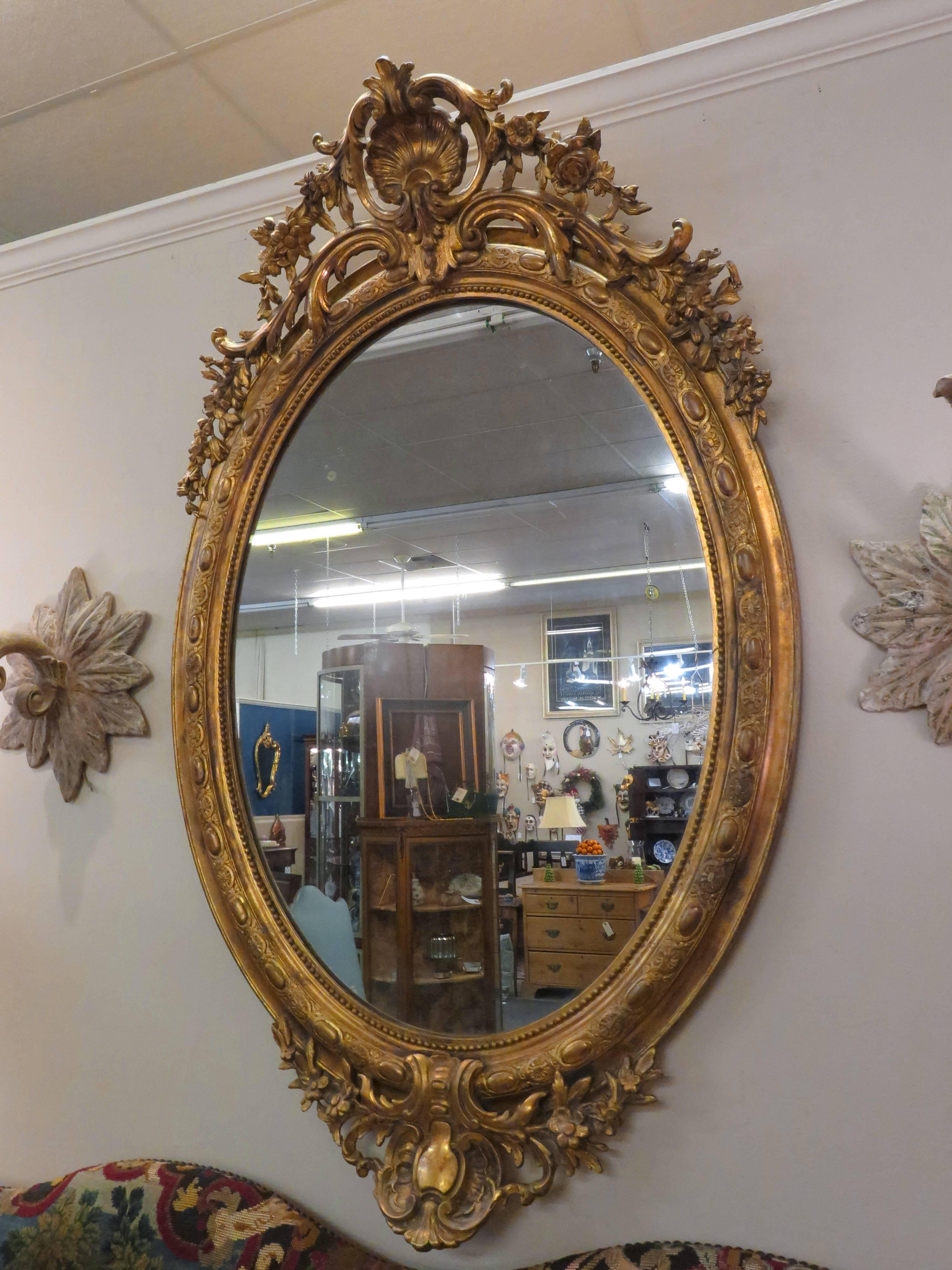 Late 19th century, circa 1870. The mirror has a pierced scrolling crest flanked by floral trailing garlands, with an egg and dart carved border and a further crest and garland carved base.