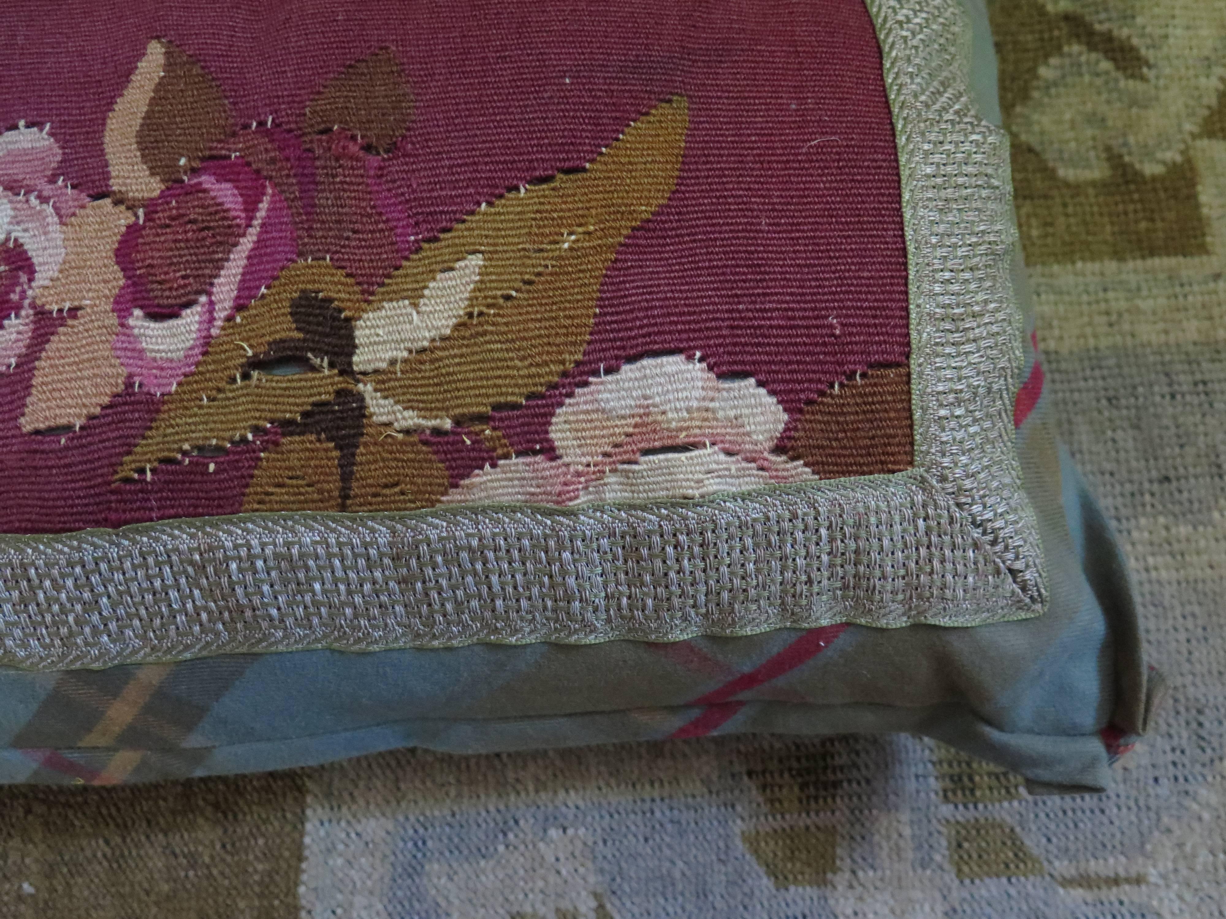 Pair of 19th century needlepoint pillows with lovely rose color and florals. Needlepoint is framed by plaid that has same rose color accent. Down filled.