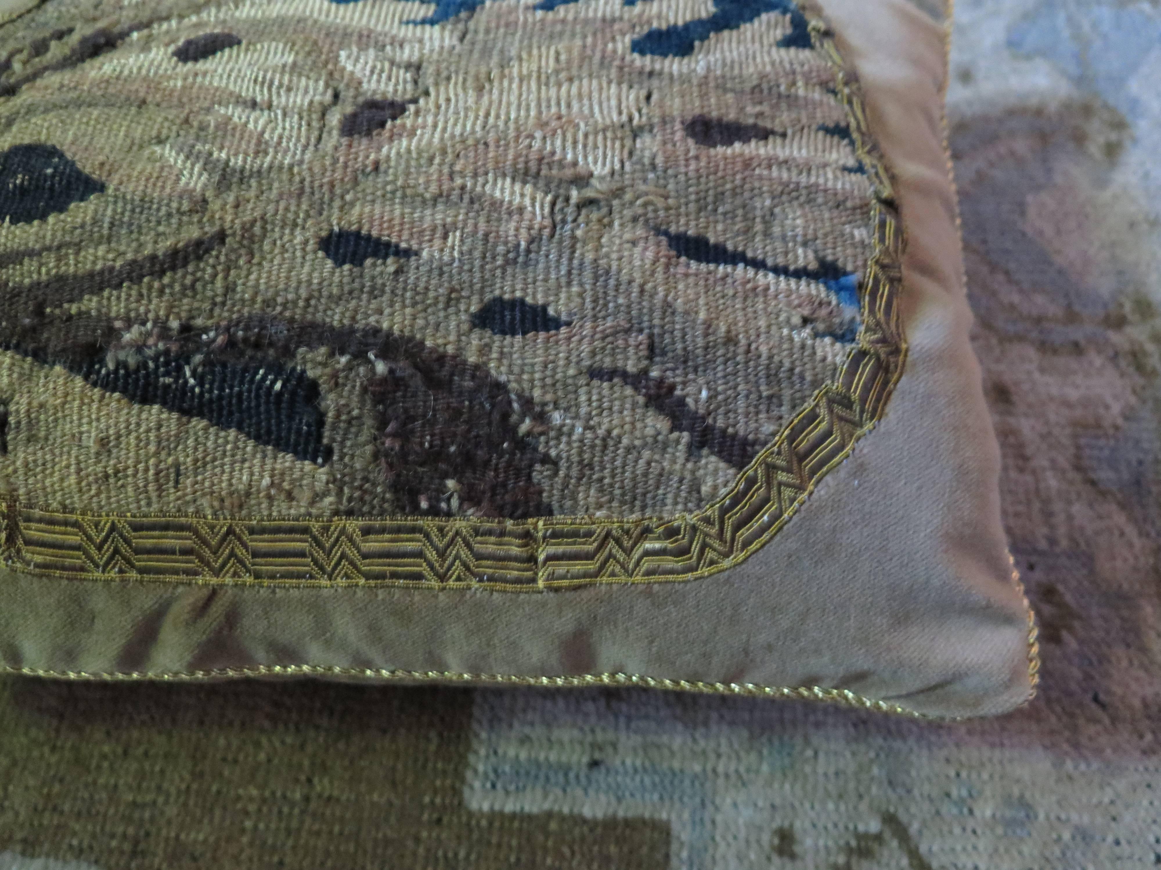 18th Century tapestry pillow in soft tan silk velvet. Pillow is edged with gold braid. Tapestry is framed in antique metallic gold ribbon. Down filled.