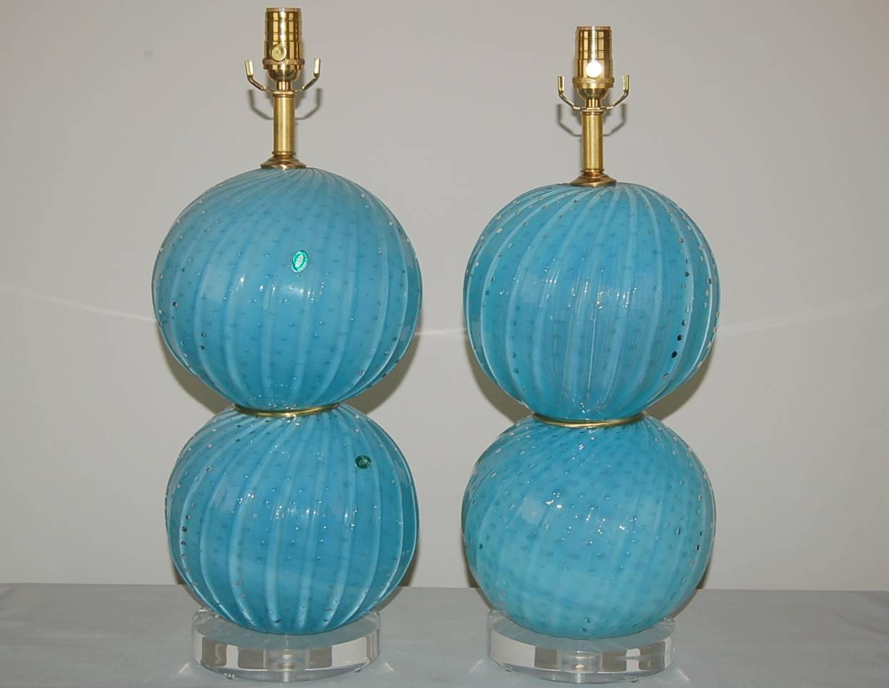 Matched pair of vintage Murano table lamps by Alfredo Barbini, in an intence AQUA BLUE OPALINE. Each ball has thick diagonal ribs and is filled with controlled bubbles, not to mention the ethereal aura of color, thanks to the Opaline. 

Lamps