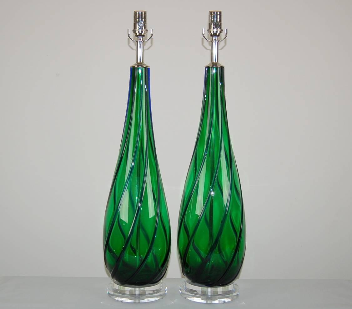 These plus-sized beauties are attention getters, vivid emerald green with applied glass ribbons of contrasting cobalt blue. The spiraling of the applied glass creates a spectacular diamond-pane optic. 

They stand 28 inches from tabletop to socket