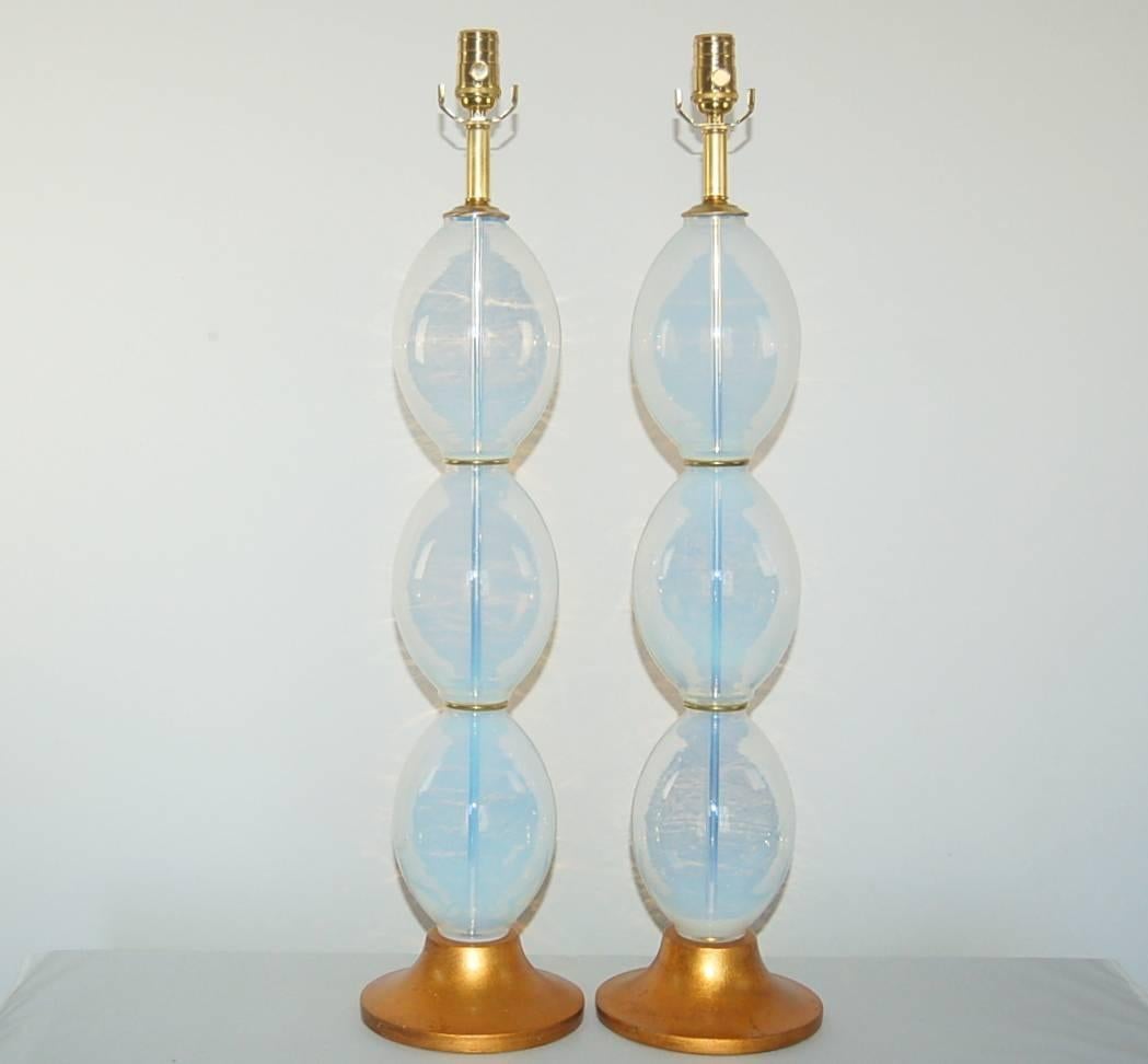 These tall stacked 'Eggs' lamps are vintage Murano table lamps made of WHITE OPALINE. Because of the opaline, the eggs read a very SOFT BLUE, and a small amount of golden light reflects through from the gold leafed bases. These lamps have a very