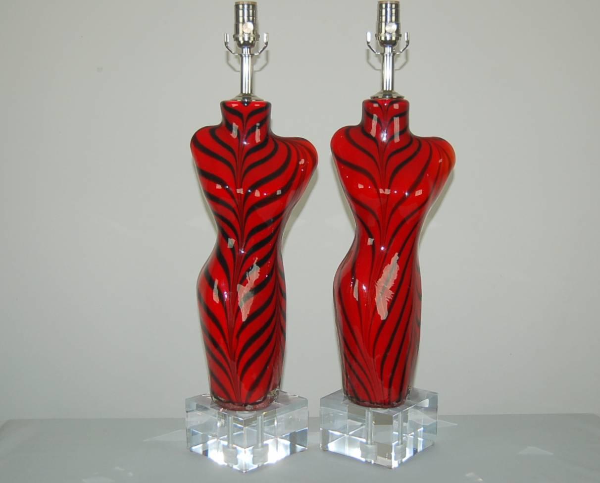 A matched pair of Murano glass Venus de Milo table lamps in ruby red and black tiger stripes, handblown into a mold. Set on large Lucite blocks, they make an imposing pair, circa 1980.

The lamps measure 26 inches from tabletop to socket top. As
