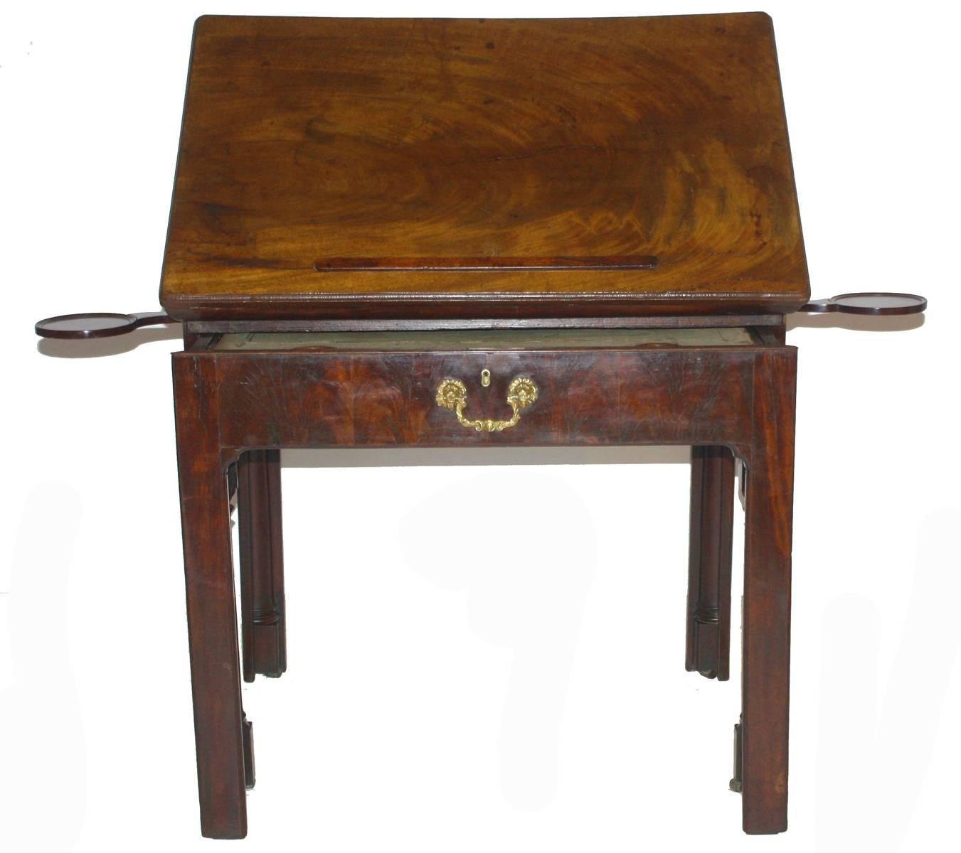 an 18th century, English architect's drawing table / desk of mahogany, the hinged top adjusts to various angles, the table / drawer extends as a writing/working surface with old worn baize top, it opens to reveal compartments for storage, small