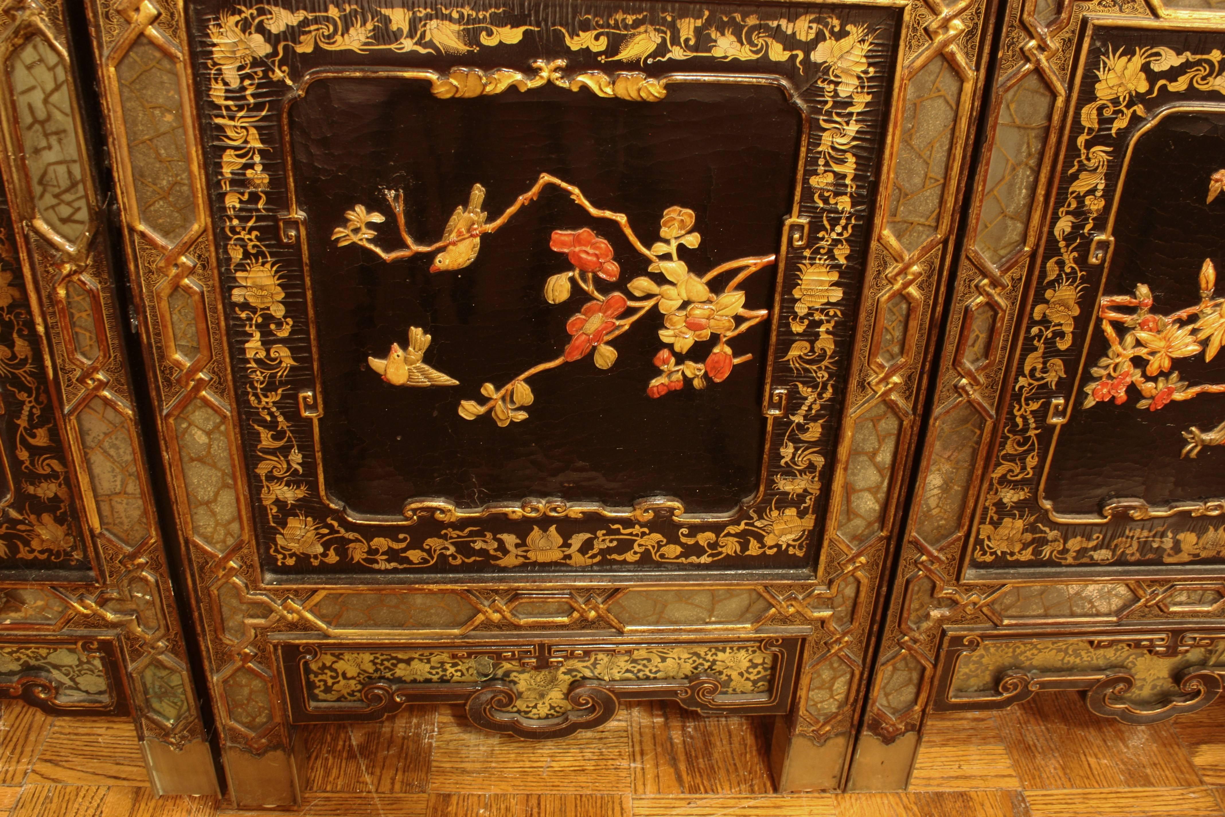 An extremely fine 19th century Chinese screen of hardwood frame inset with black lacquer panels. The panels on one side display people performing everyday and celebratory acts and birds resting in trees surrounded by floral, both made with overlays