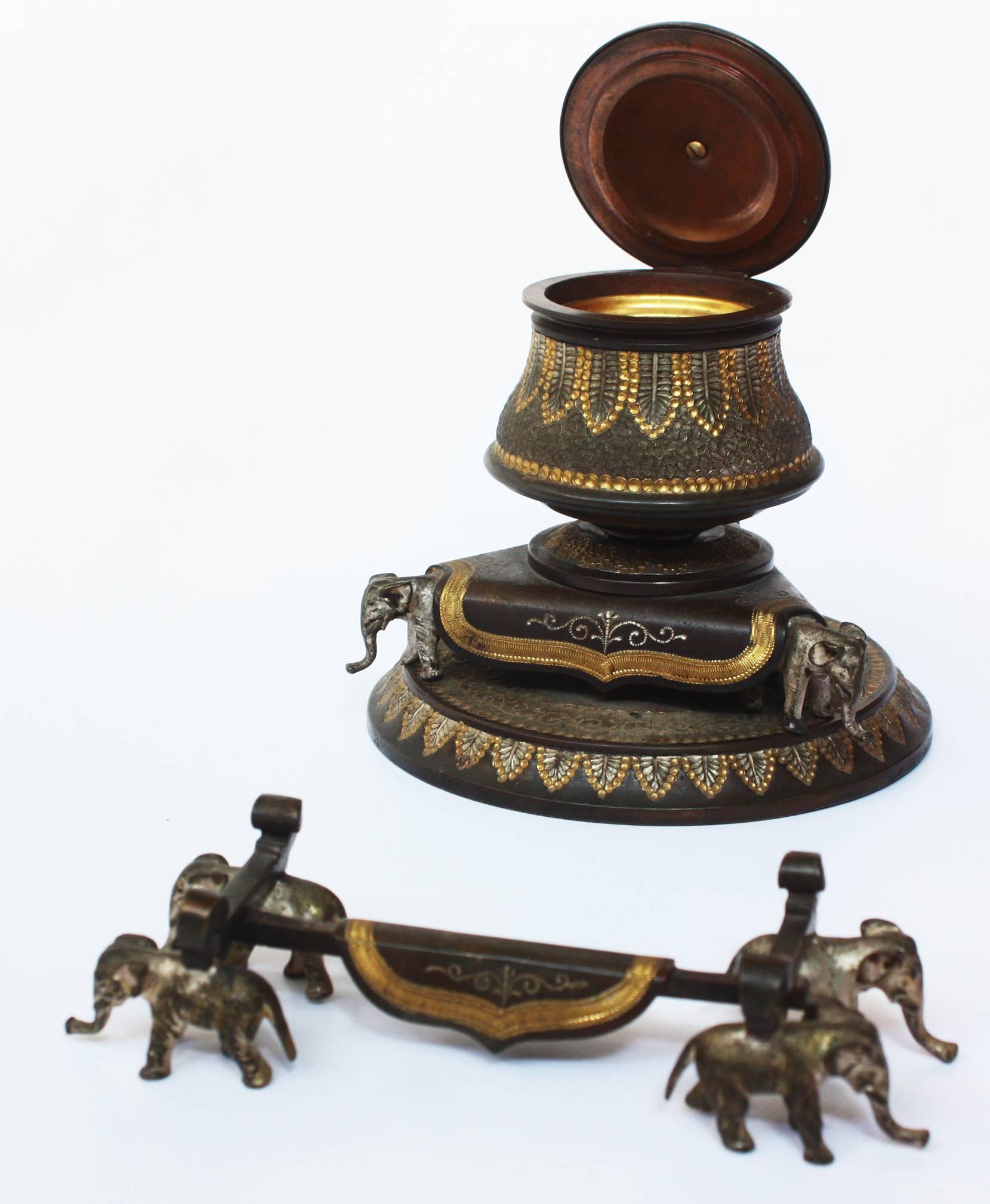 A patinated and gilt bronze inkwell, highly decorated with hammered / embossed design / pattern, three tiny elephants on a round 4.75