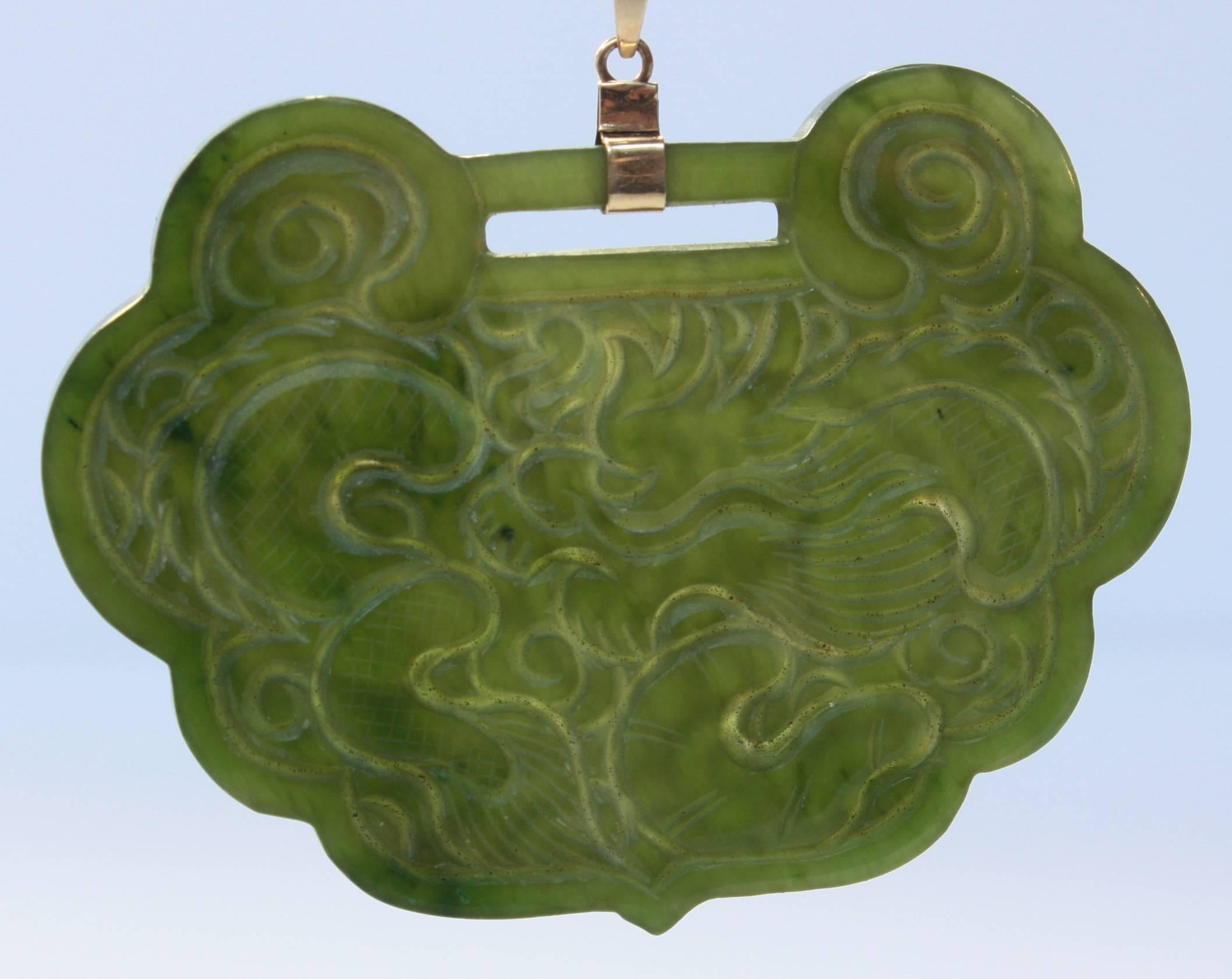 Hand-carved green jade pendant. Carved dragon on one side and koi on the reverse side.