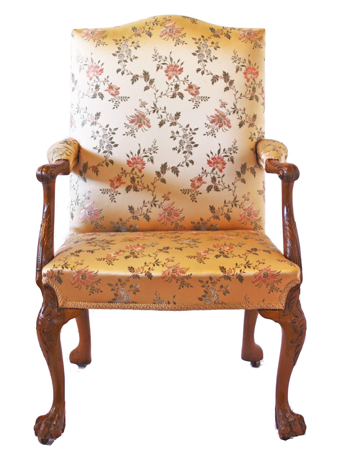 An exceedingly fine Georgian elbow chair in a light golden walnut with hairy paw feet (later castors) and crown and acanthus carving on the front legs and finely detailed acanthus carving on the arms. The seat and back are upholstered and pleasingly