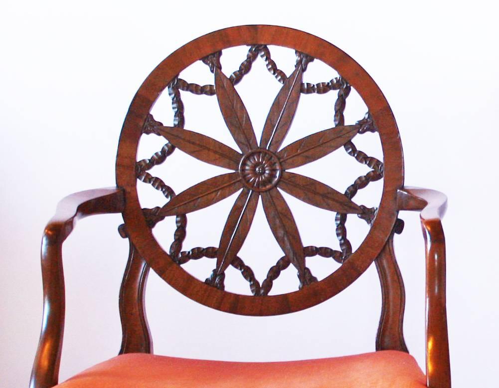 A pair of George III mahogany Hepplewhite period wheel back open elbow chair in the manner of Robert Adam (Scottish 1728-1792), bearing the characteristic circular pierced splat enclosing palm leaves radiating from a central patera and intersected