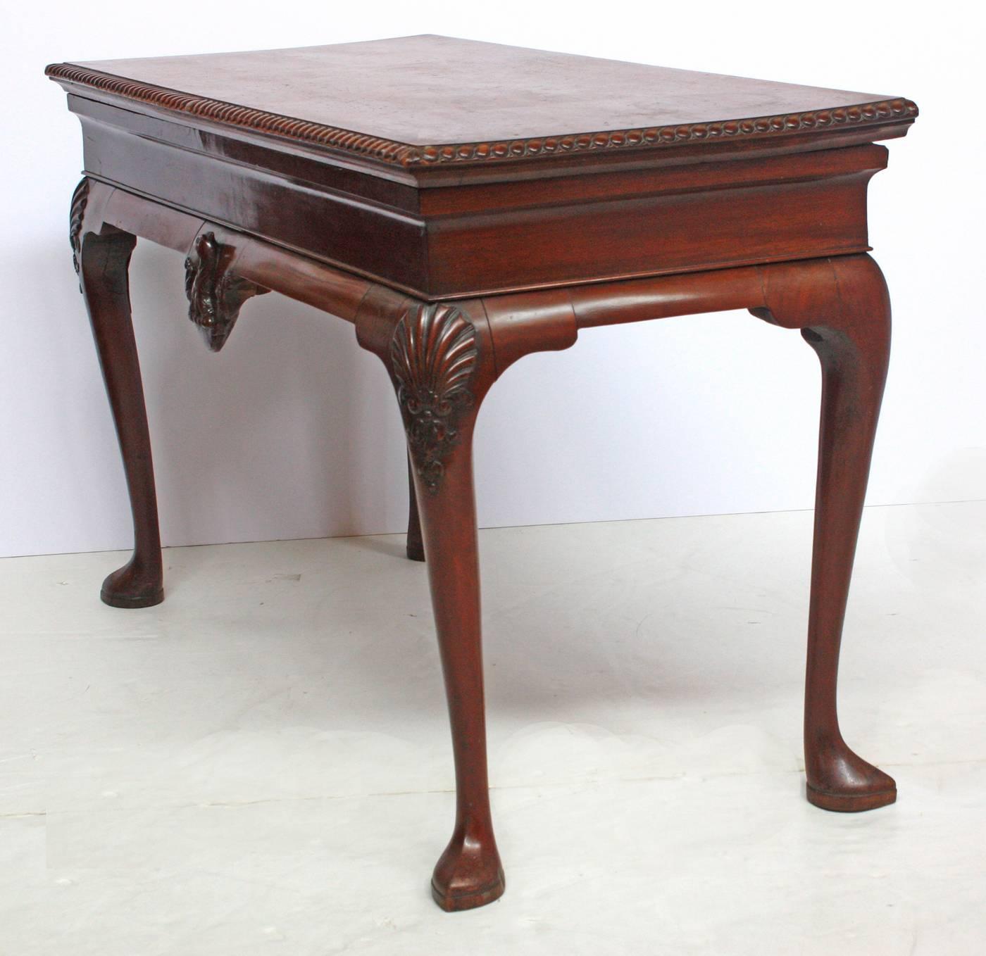 A period Irish / George II mahogany slab / serving table with armorial crest decoration (a cock's head erased) on the center of the apron having a gadrooned edge top (later replacement of missing / lost original marble slab top), slight cabriole