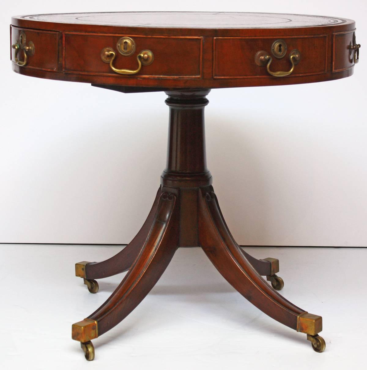 A George III drum table with mahogany and leather inset rotating top, four drawers, pedestal base, on casters, gun barrel stem.

(Turned column pedestal with four splayed legs).