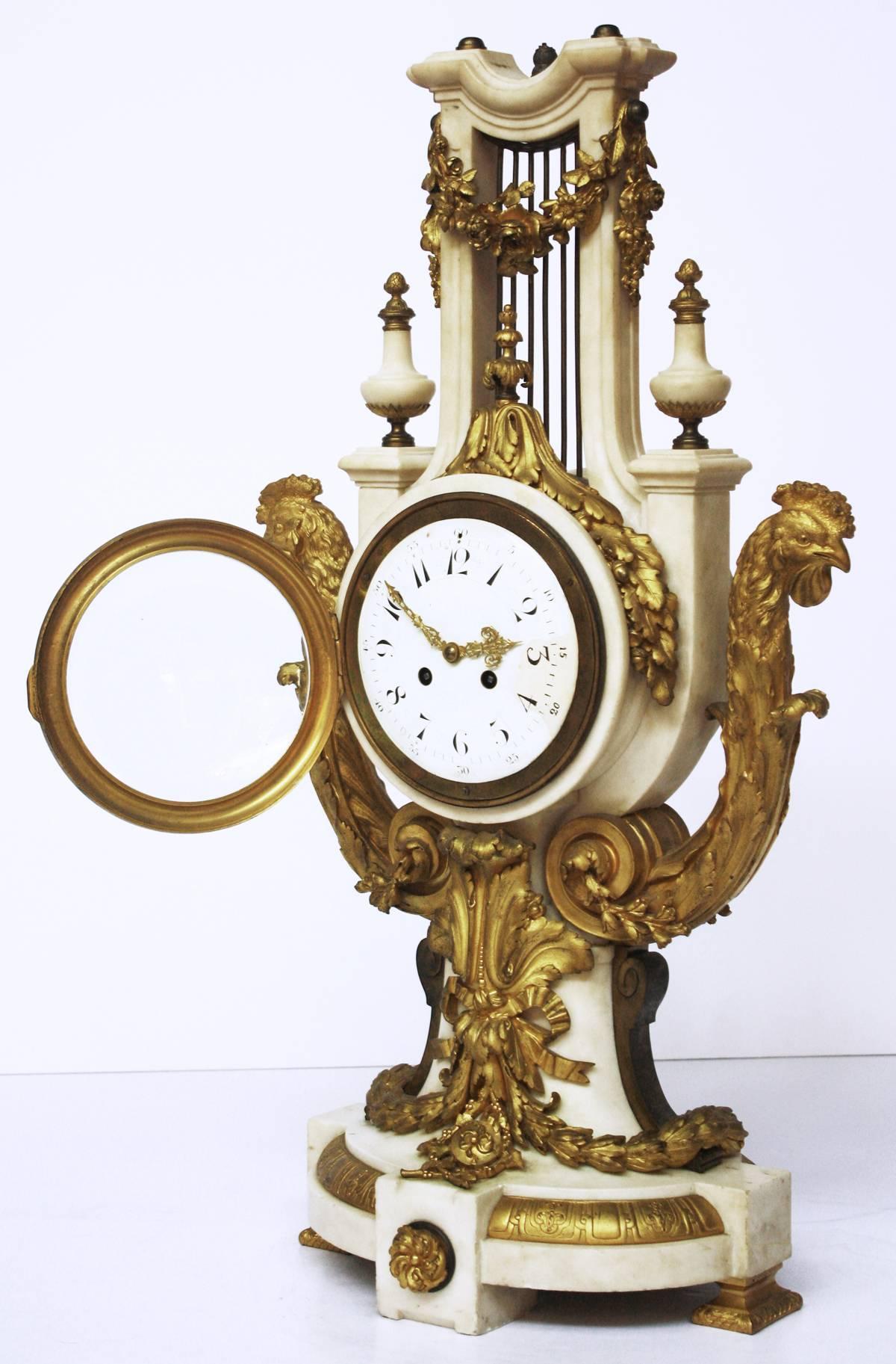 An elaborate French clock, Louis XVI-style lyre-form of marble with gilt bronze mounts: in the form of floral swags, garlands of oak leaves (with acorns), festoons of laurel leaves, cock's heads, acanthus leaves, ribbons and bows, the marble base is