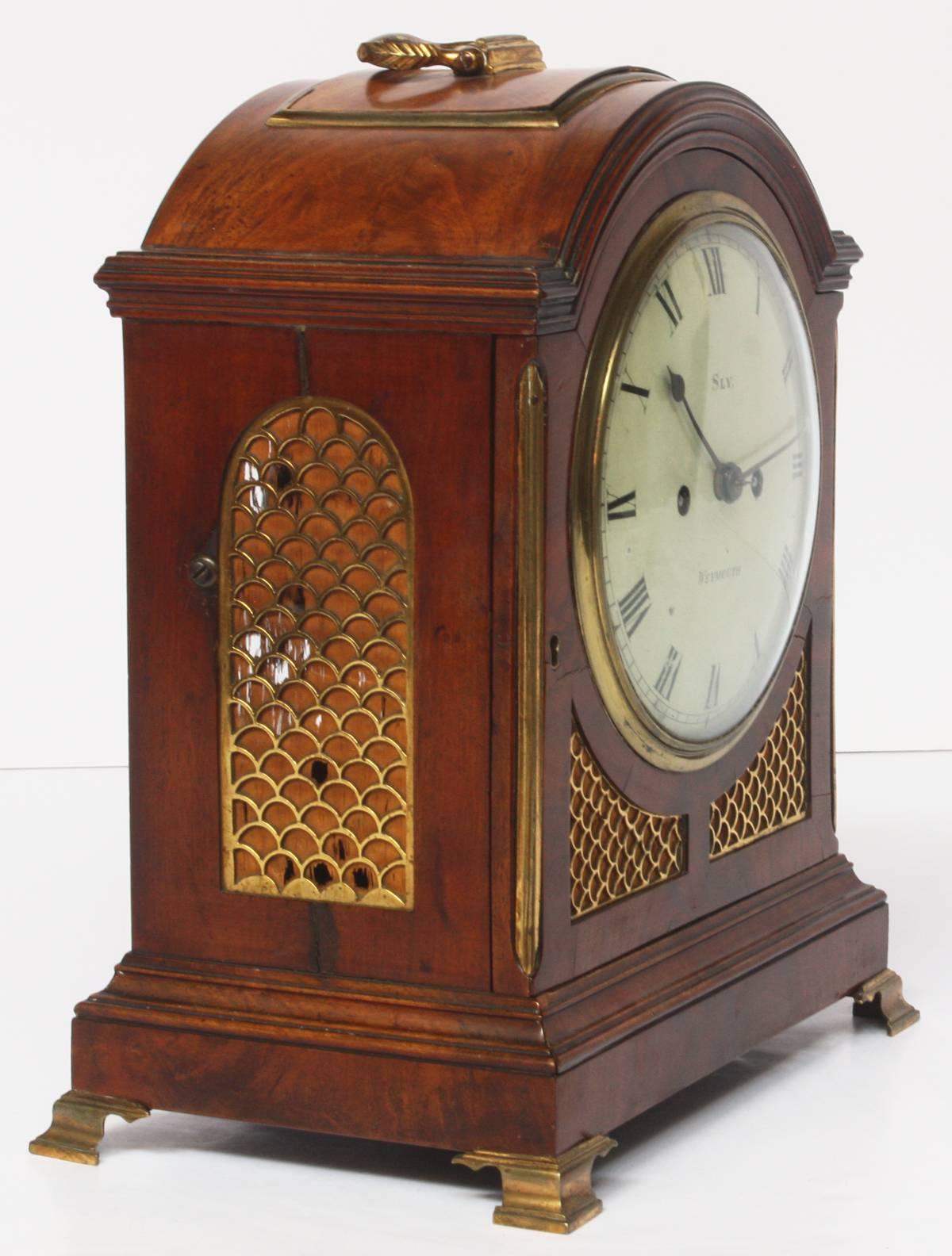 a fine George II period mahogany bracket clock by Sly, Weymouth, England, on top is a brass carrying handle and a full opening front door with a cast brass bezel and convex glass, the white convex enamel 7