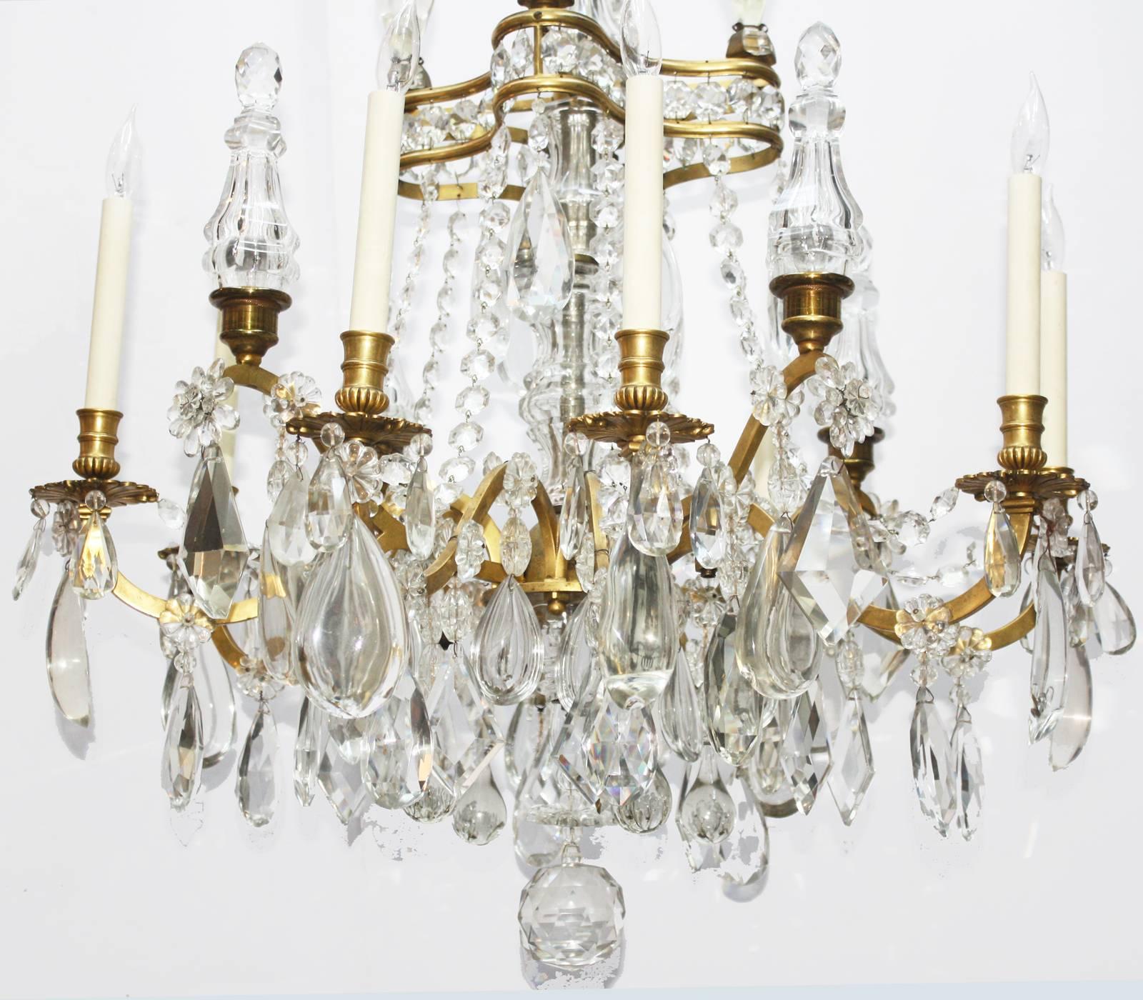 Beautiful French crystal chandelier with canopy of arched gilt bronze arms hung with flower shaped crystal beads with oval crystal drops, over a cut crystal column. A centre double banded quatrefoil of gilt bronze separated by octagon jewel