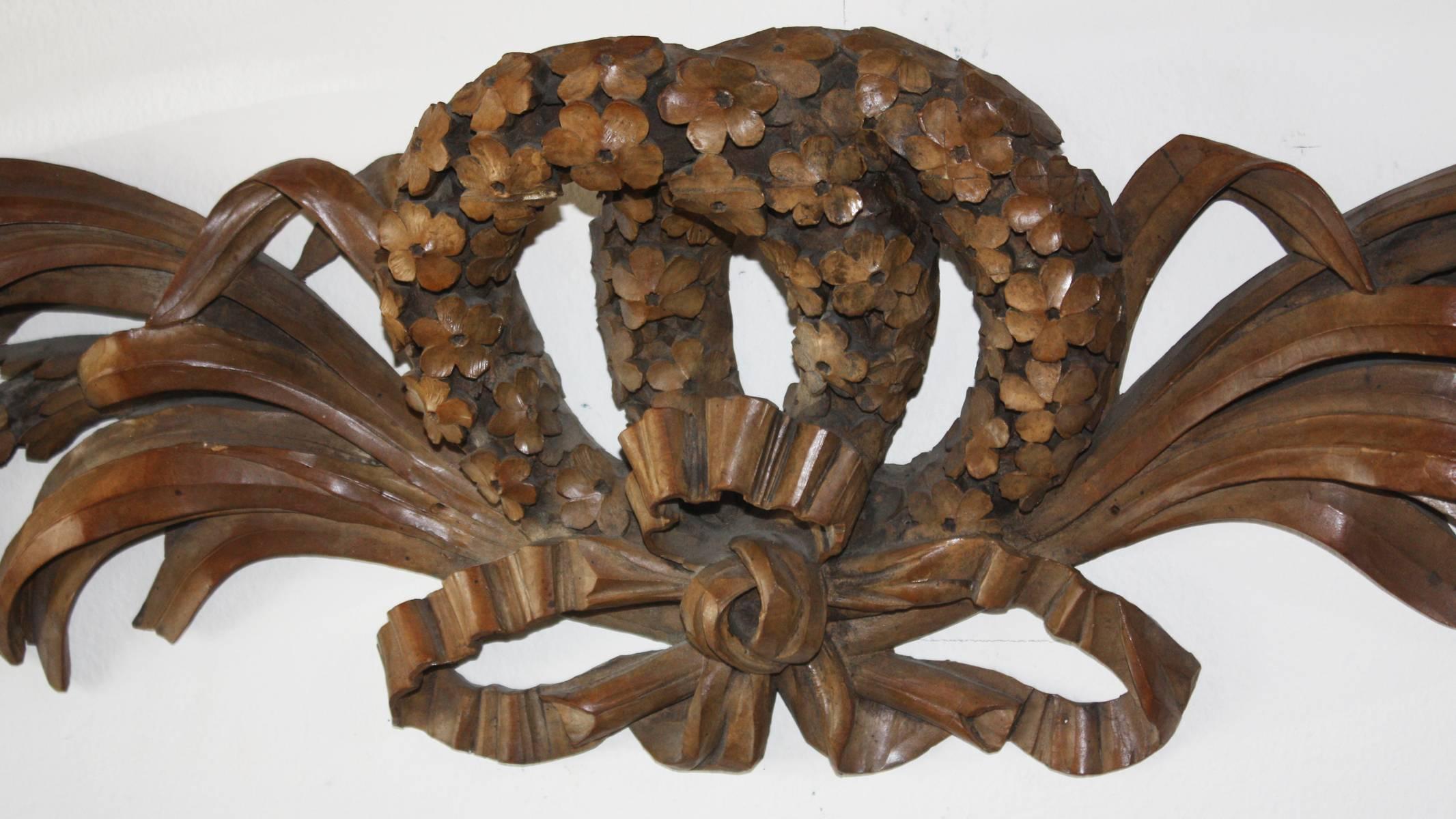 A highly decorative and well carved five section wall ornament, with a centered double-wreath comprised of beautifully carved flowers, flanked by floral swags decorated with flowers, fruit, berries and leaves, with bows at each sides. After Grinling