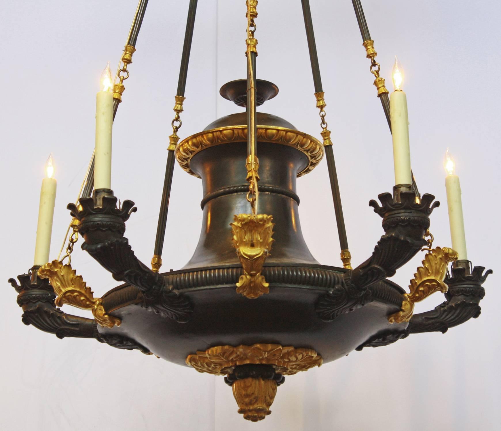A French Empire patinated and gilt bronze five-arm Argon chandelier with a bowl base with five arms and five supports with leaf forms at their base, which has been converted to electricity.