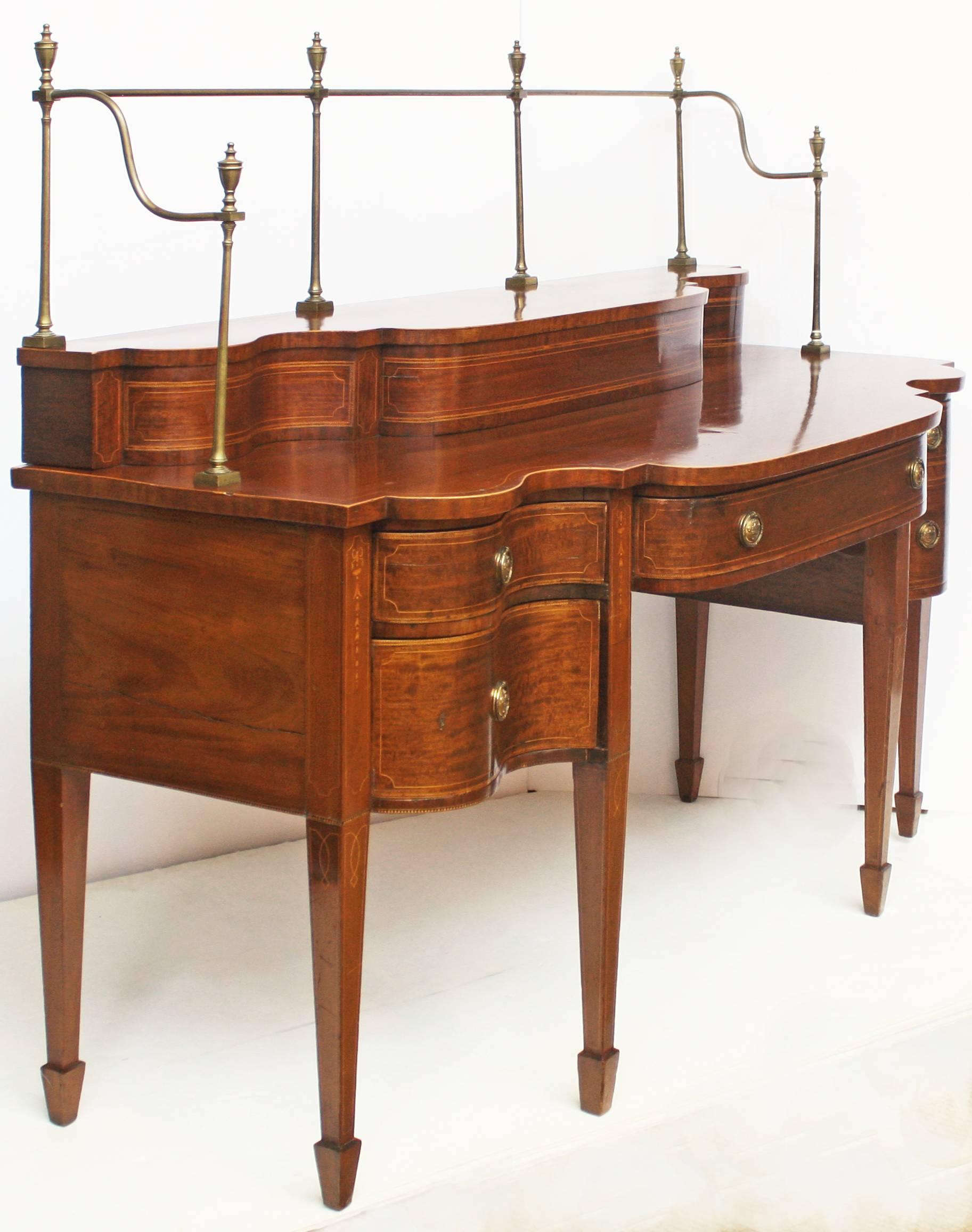 Georgian mahogany serpentine sideboard with bow and bell flower stringing on each leg. Square tapering legs terminating in spade feet. Long center drawer is flanked on left by two short drawers and on right by a cellarette that mimics two short